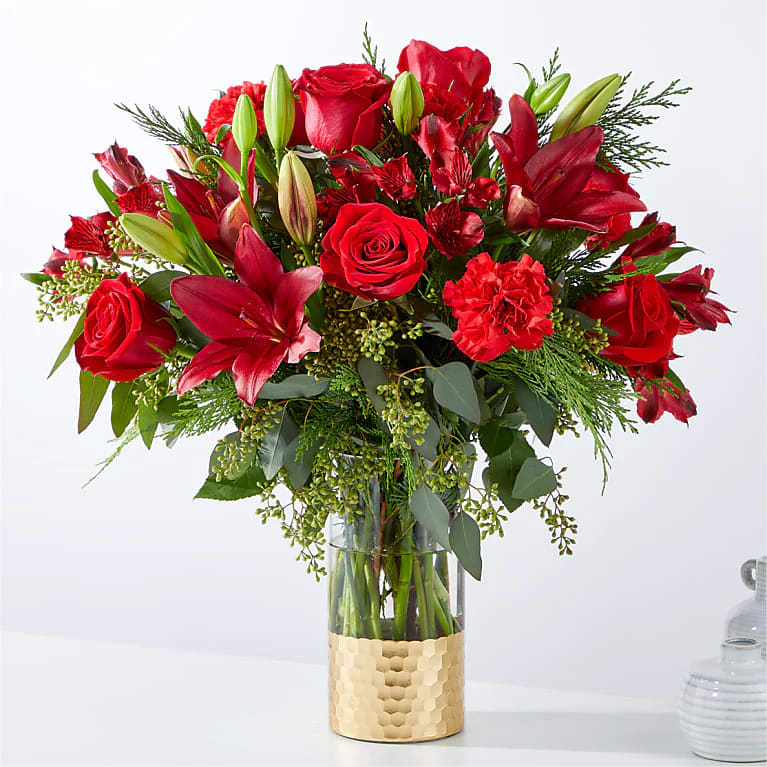 Red Velvet Christmas - Red roses Red lilies Red carnations red alstroemeria make up this rich vivid display of course it is finished off with fresh winter greens. 