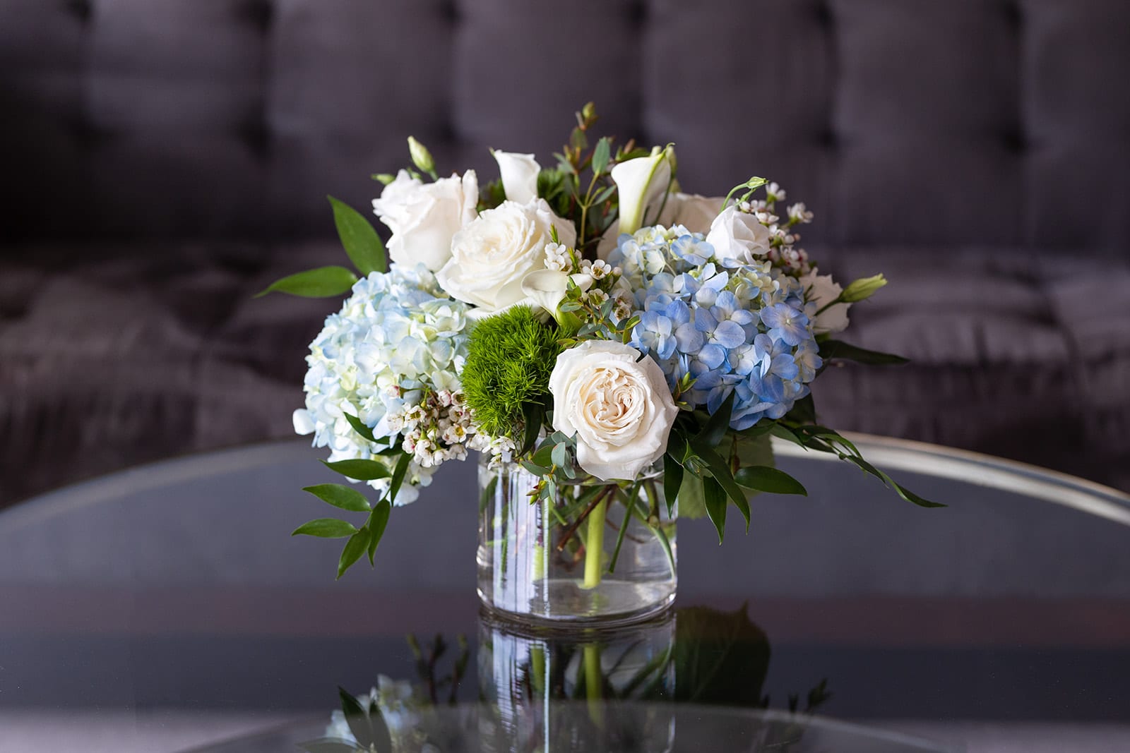 White roses and blue hydrangeas arranged in a clear glass vase