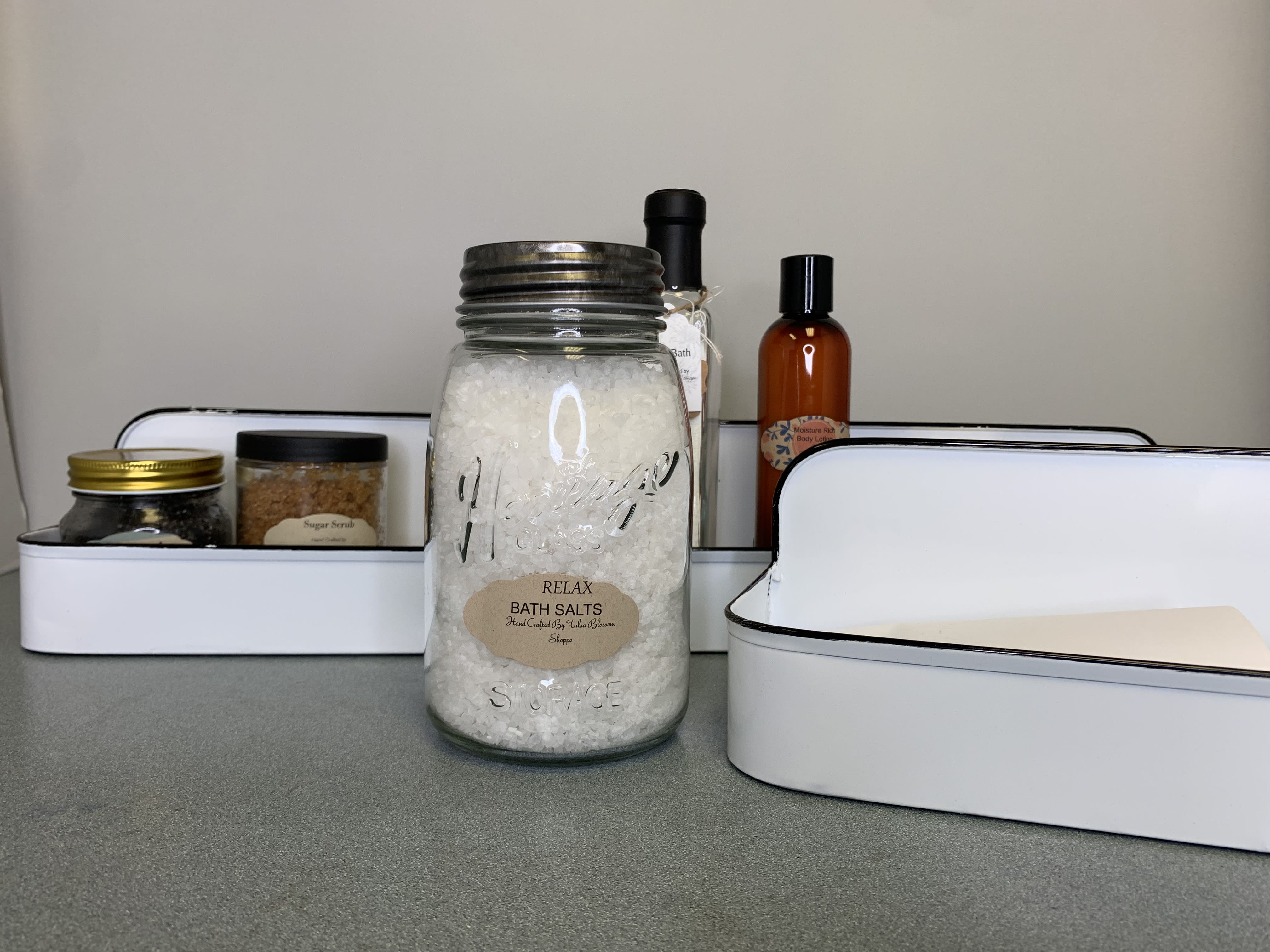 Bath salts jar with assorted spa gift items in white trays
