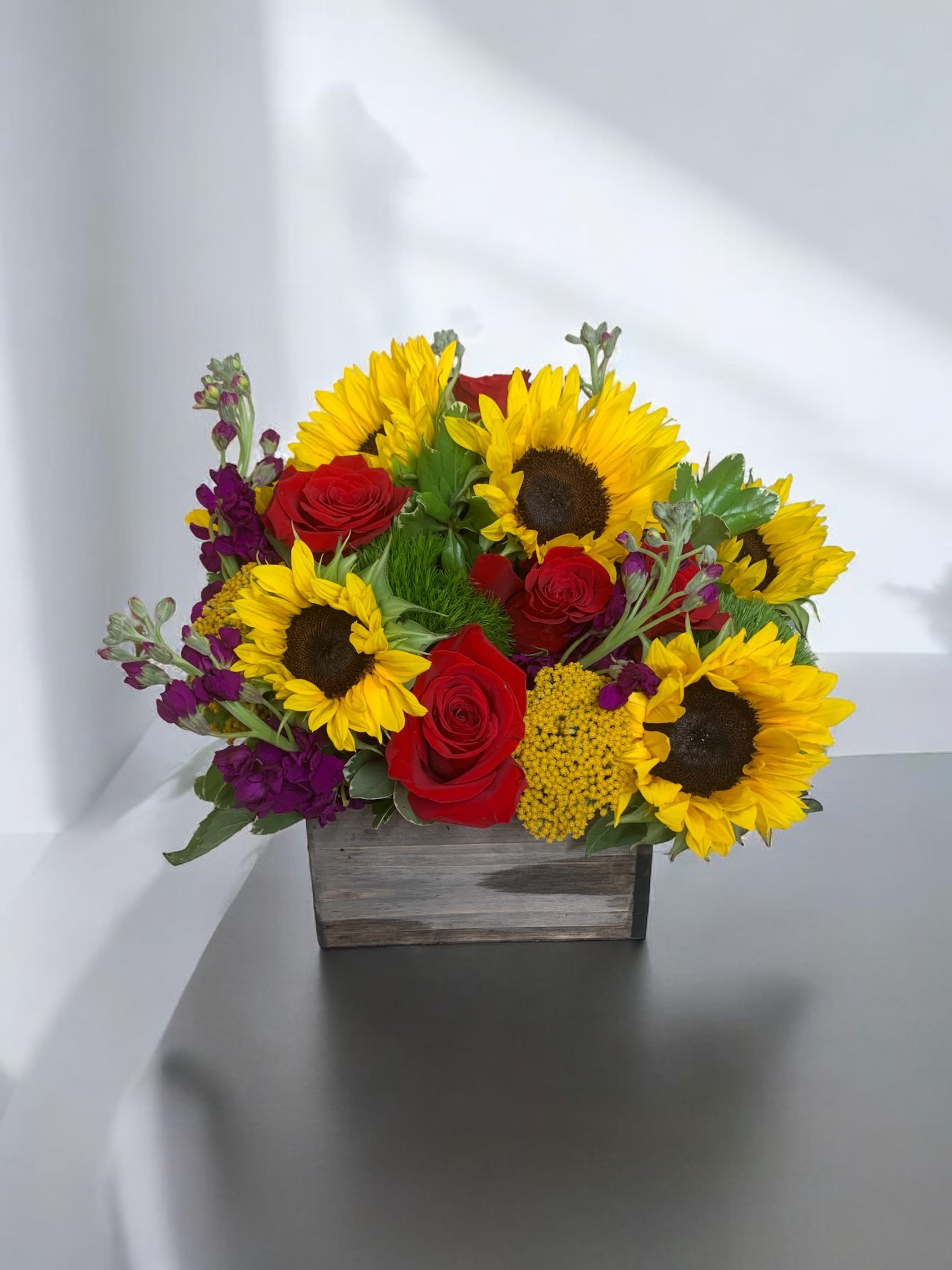 Sunflower and red rose arrangement in a wooden box