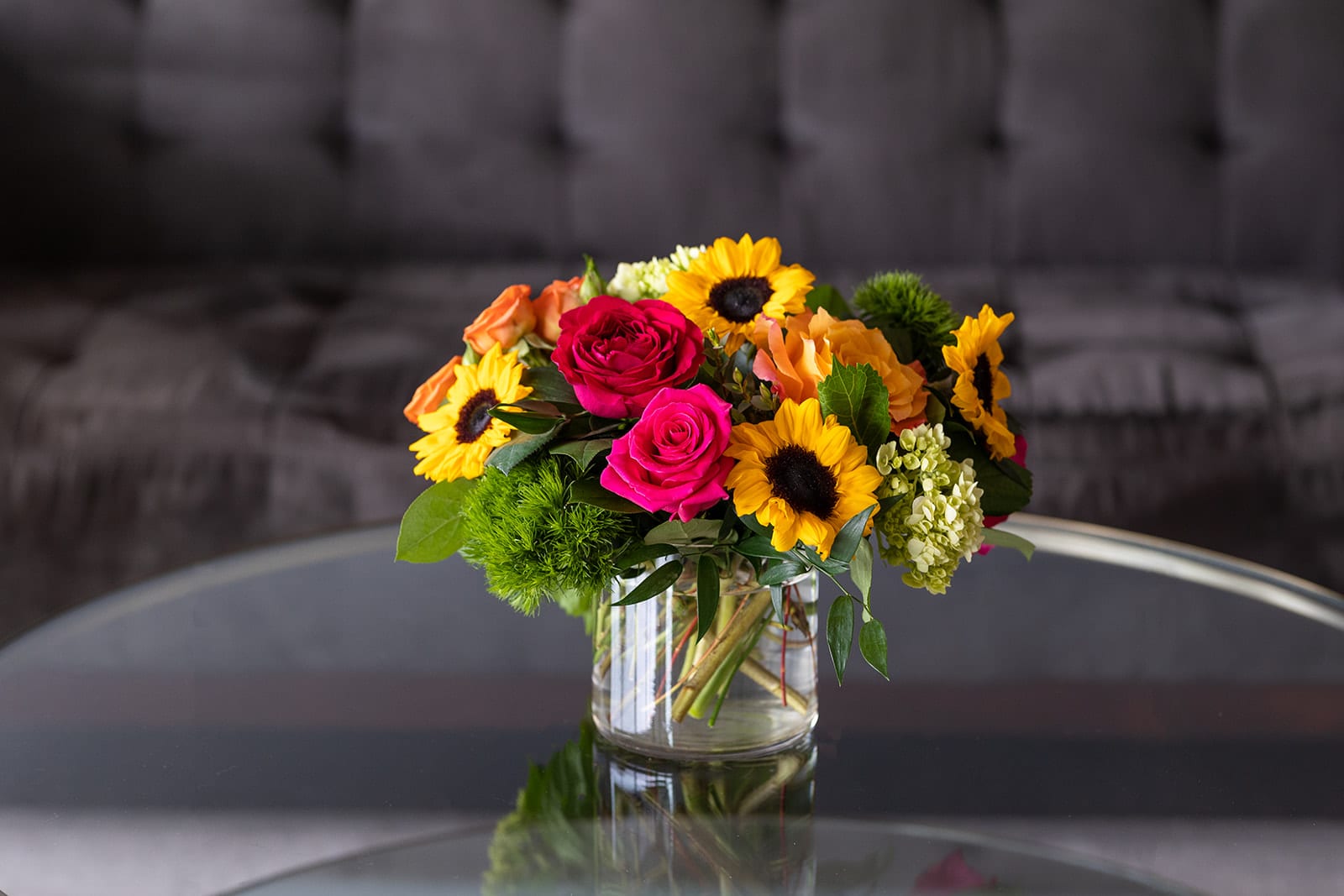 Bouquet of sunflowers and pink roses in a clear glass vase
