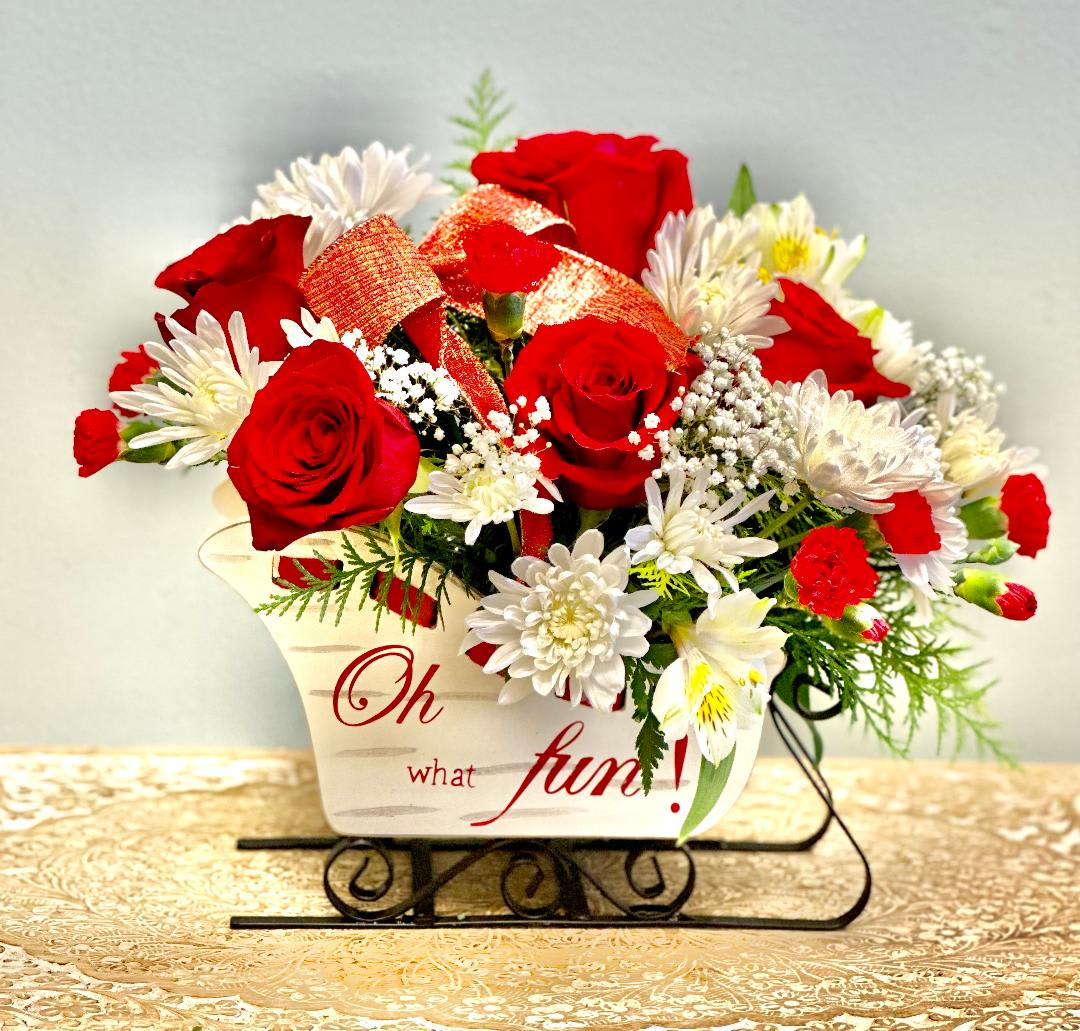 Red roses and white daisies in a decorative container with a ribbon