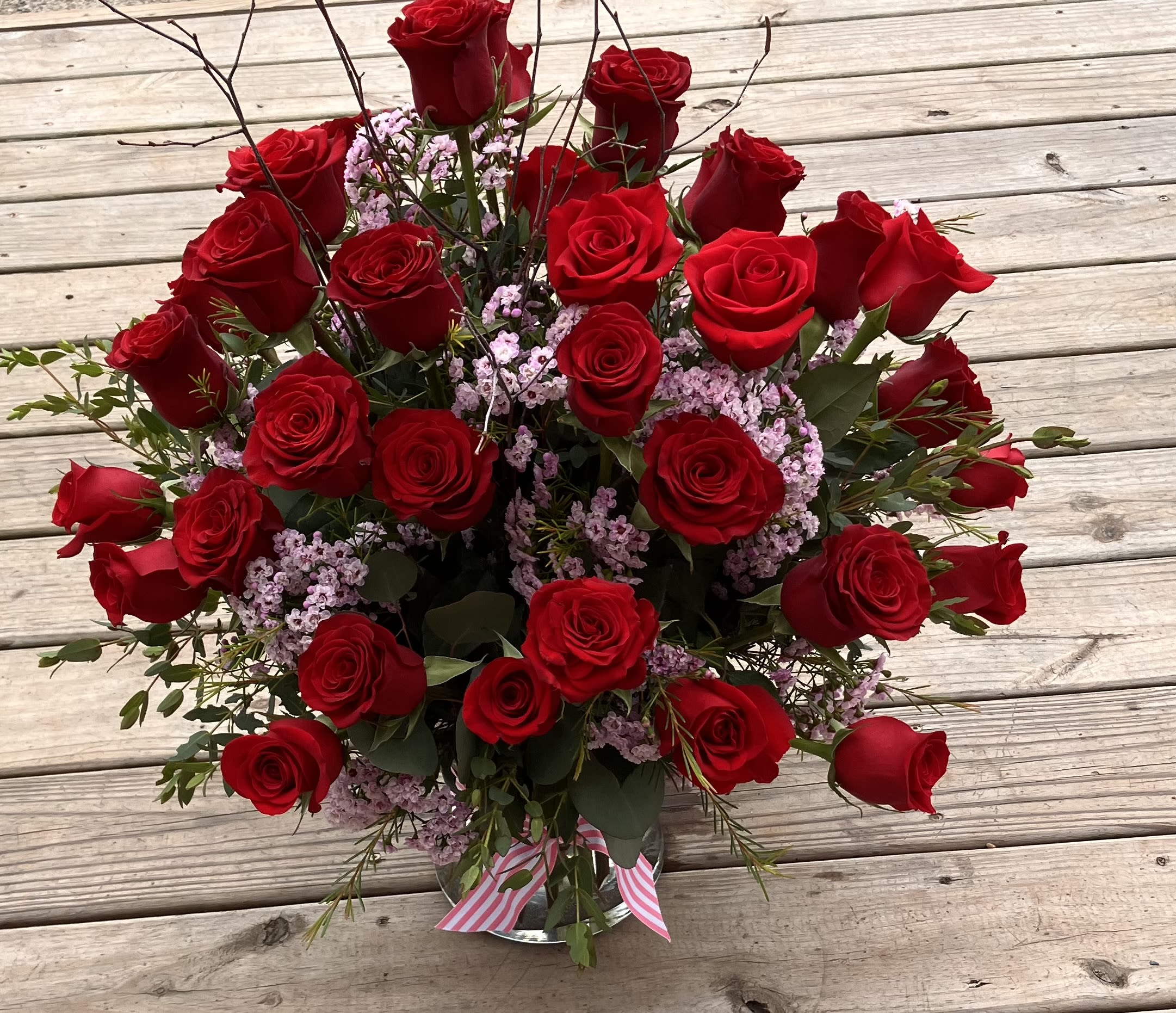 Bouquet of red roses with pink filler flowers in a glass vase