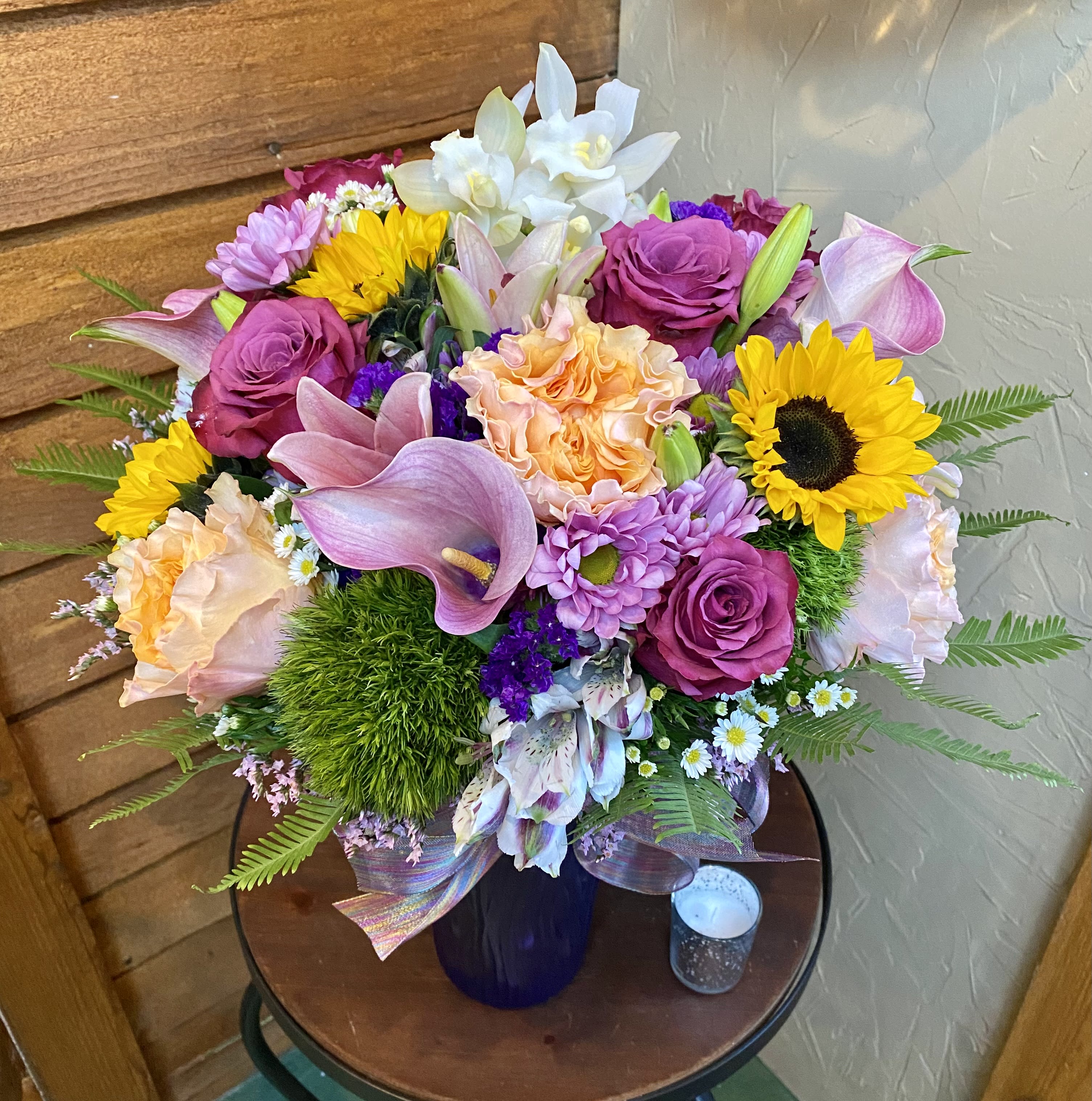Mixed bouquet with sunflowers, roses, lilies, and calla lilies in a vase