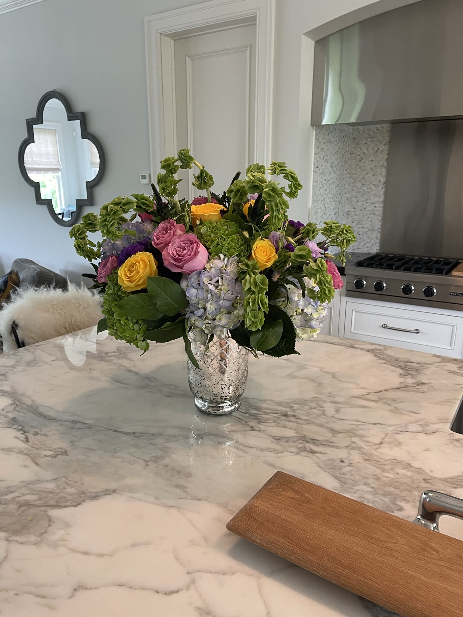 Mixed bouquet of pink, yellow, and lavender flowers in a glass vase