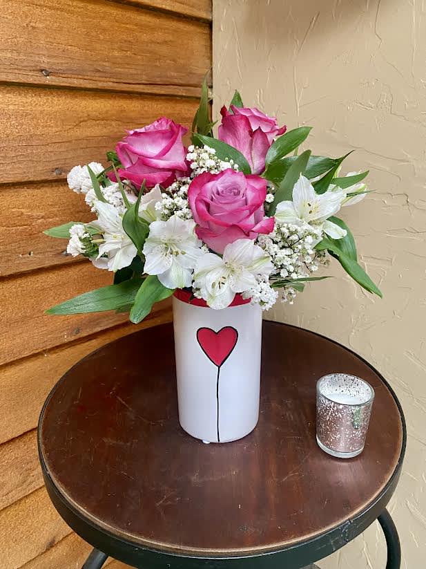 Pink roses and white flowers in a white vase with a heart design