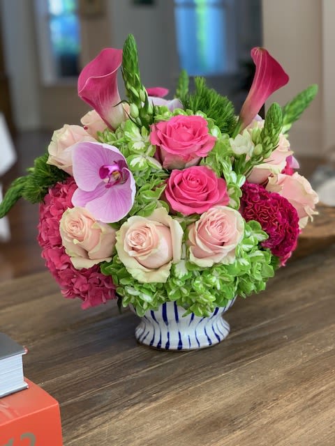 Pink roses and calla lilies arranged in a striped vase