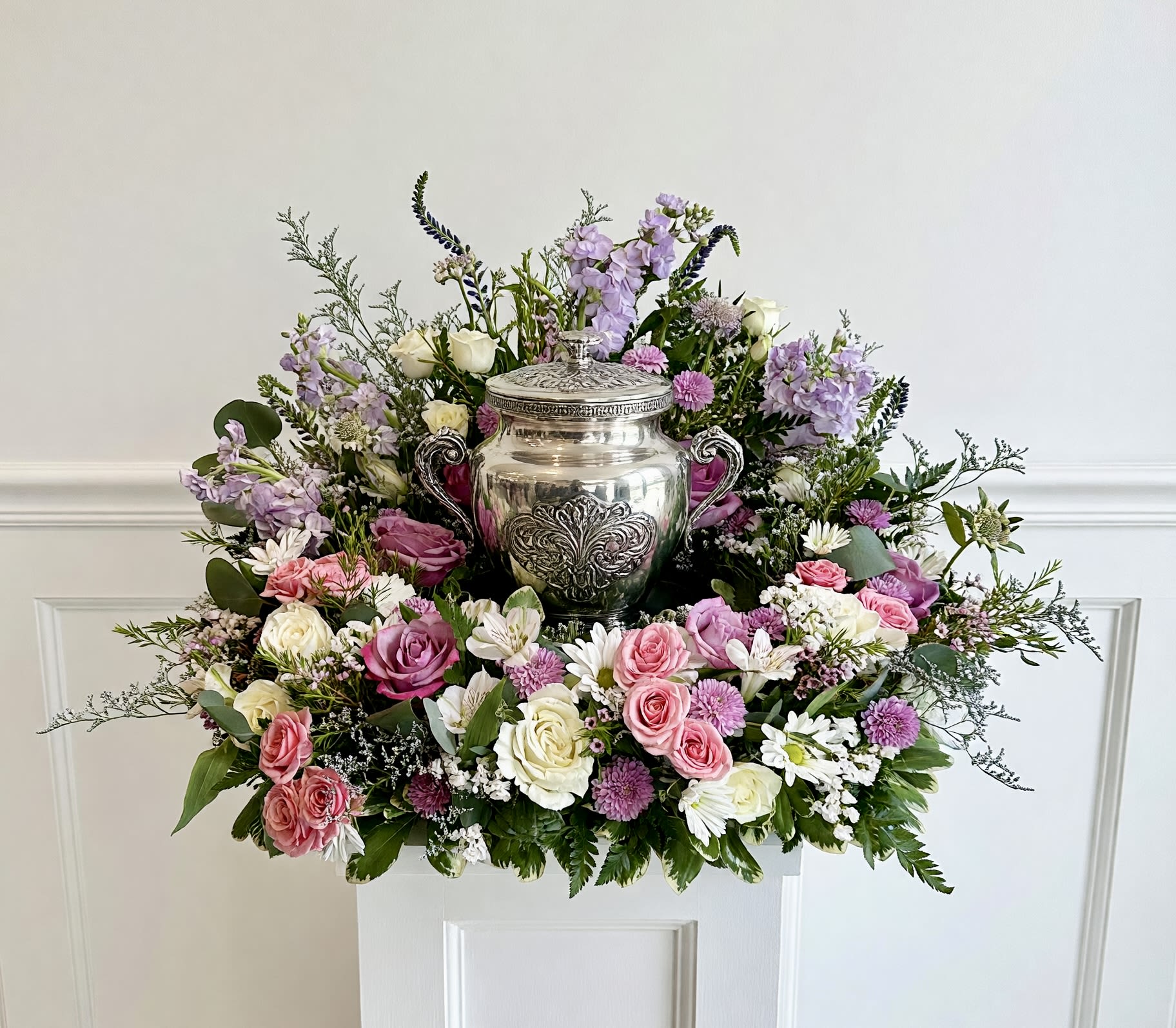 Pastel Sympathy Urn Arrangement  - A beautiful mix of soft pastel flowers, high in the back and low in the front to compliment a cremation urn. Seasonal flowers make up this soft pretty urn arrangement and can include, roses, stock, spray roses, Veronica, waxflower and daisies. 