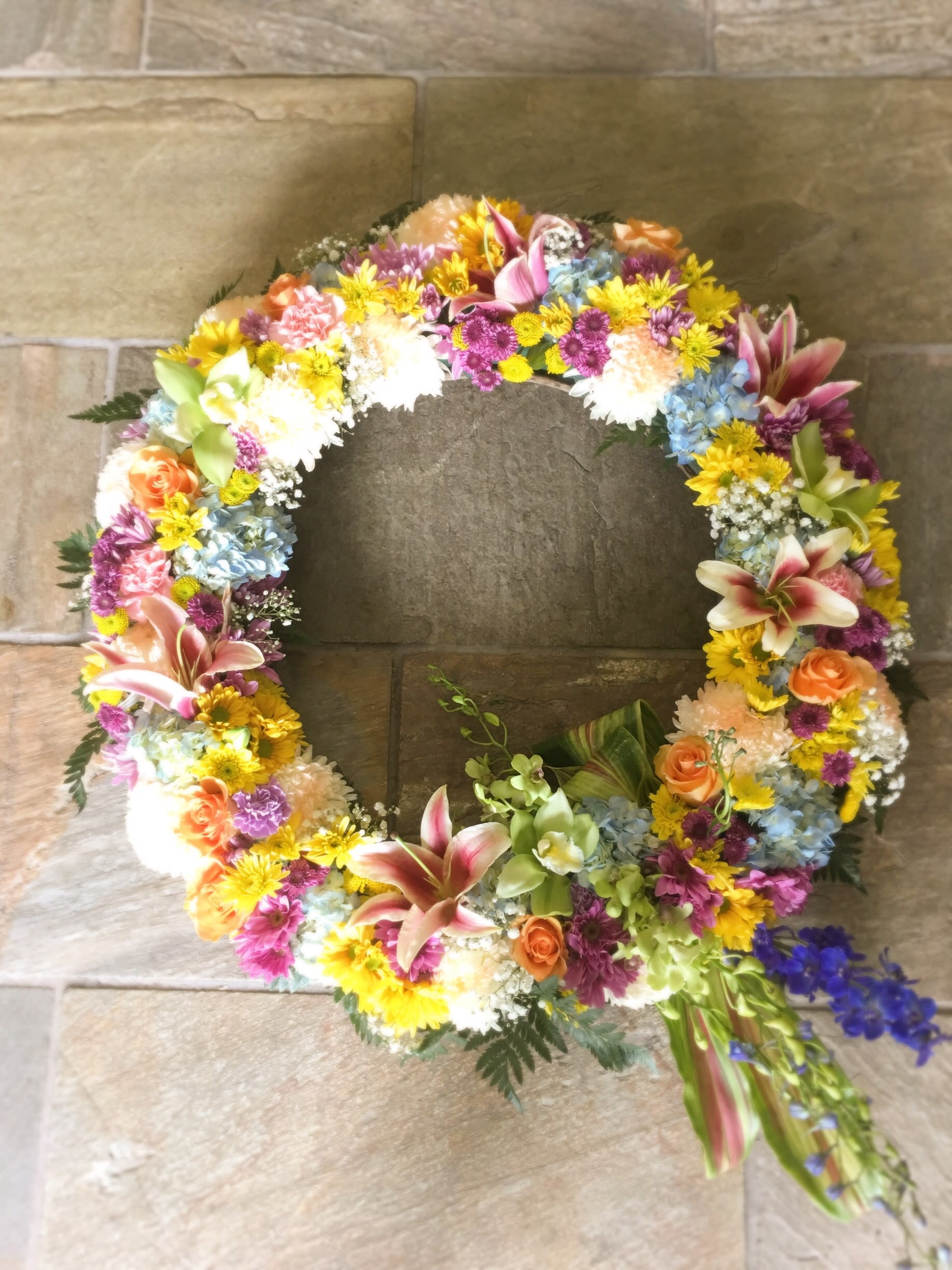 Circular floral wreath with mixed pink, yellow, blue, and orange blooms