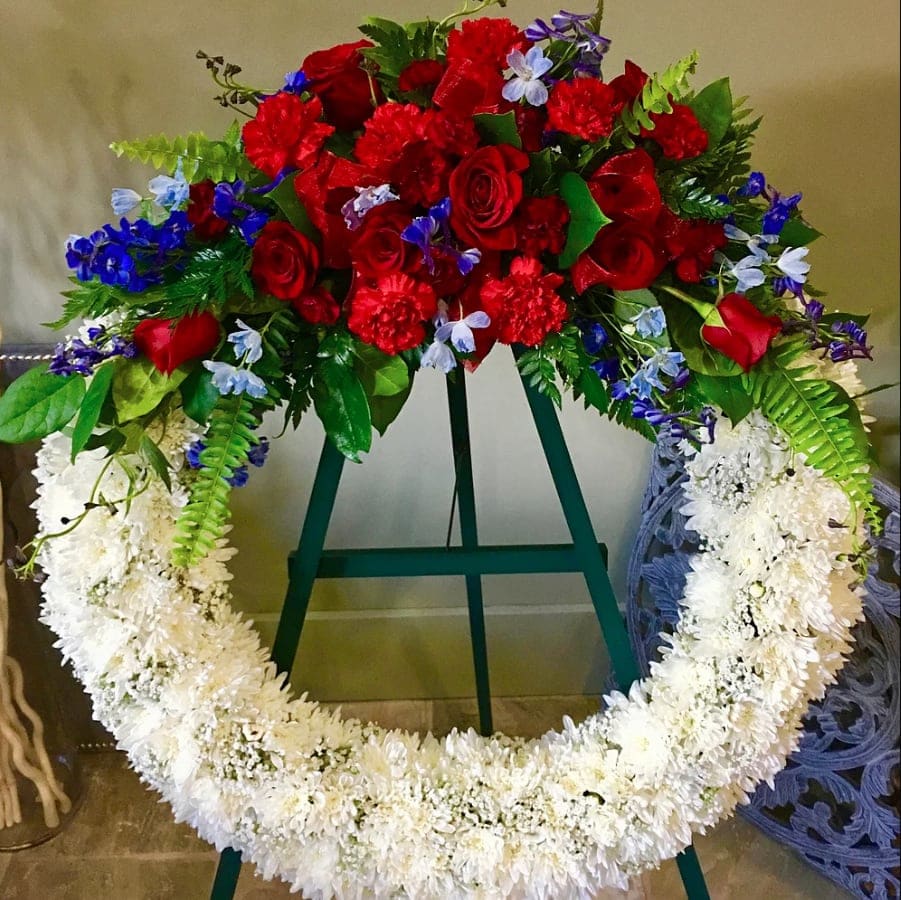 Large floral wreath with red roses and white flowers on a stand