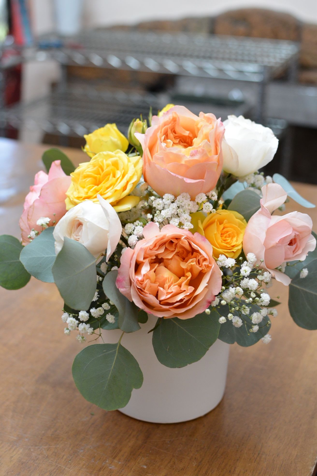 Blushing Garden - Soft, romantic, and effortlessly elegant, this arrangement combines the timeless beauty of David Austin garden roses with delicate sprigs of baby’s breath. In a dreamy palette of pastel hues, each bloom unfolds like a whisper of spring, creating an ethereal display that exudes grace and charm. Perfect for expressing love, admiration, or simply bringing a touch of gentle sophistication to any space.  cylinder vase size 5"x5", picture show white but we will use gold 