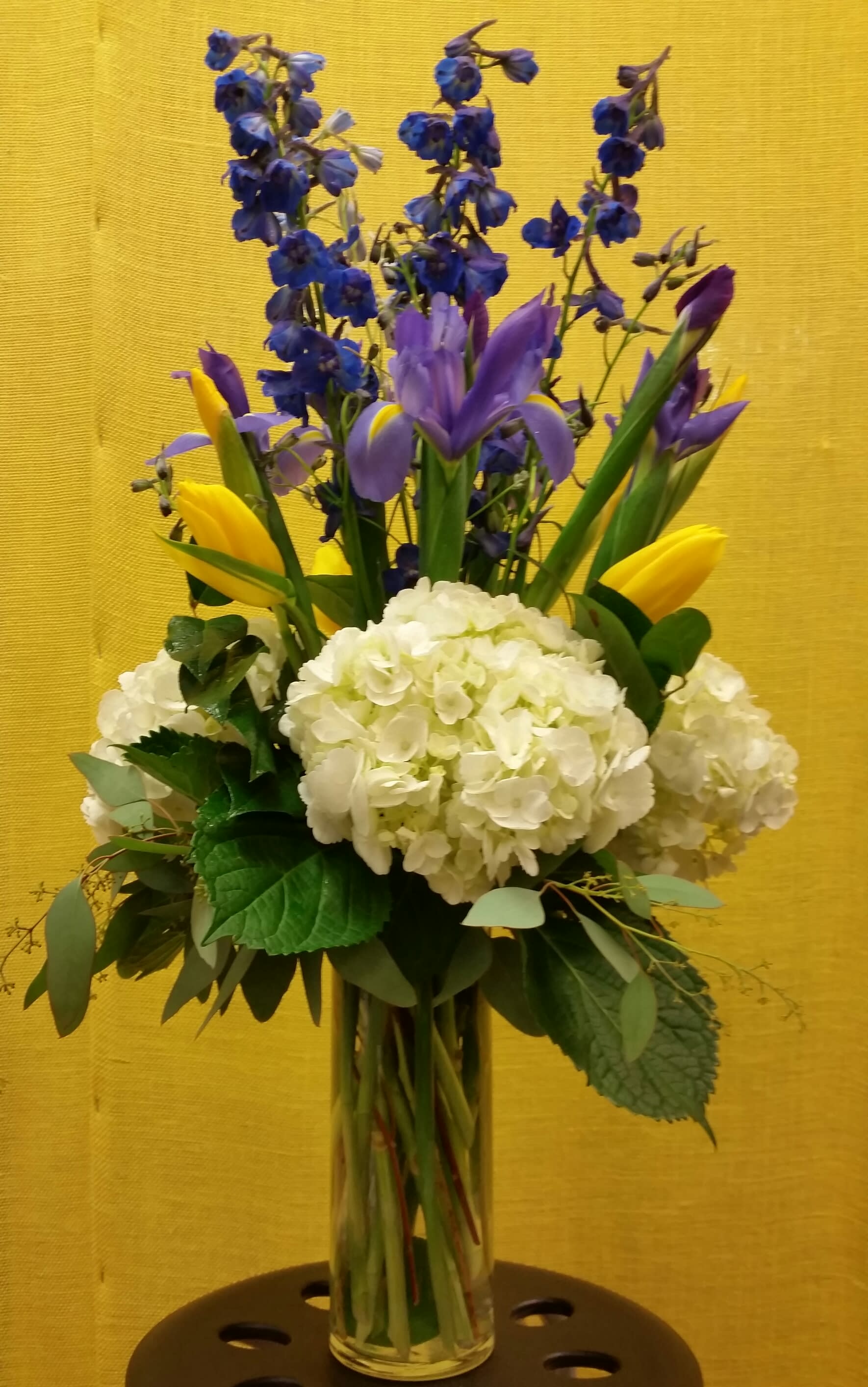 Bouquet of blue and purple flowers with white hydrangeas in a glass vase
