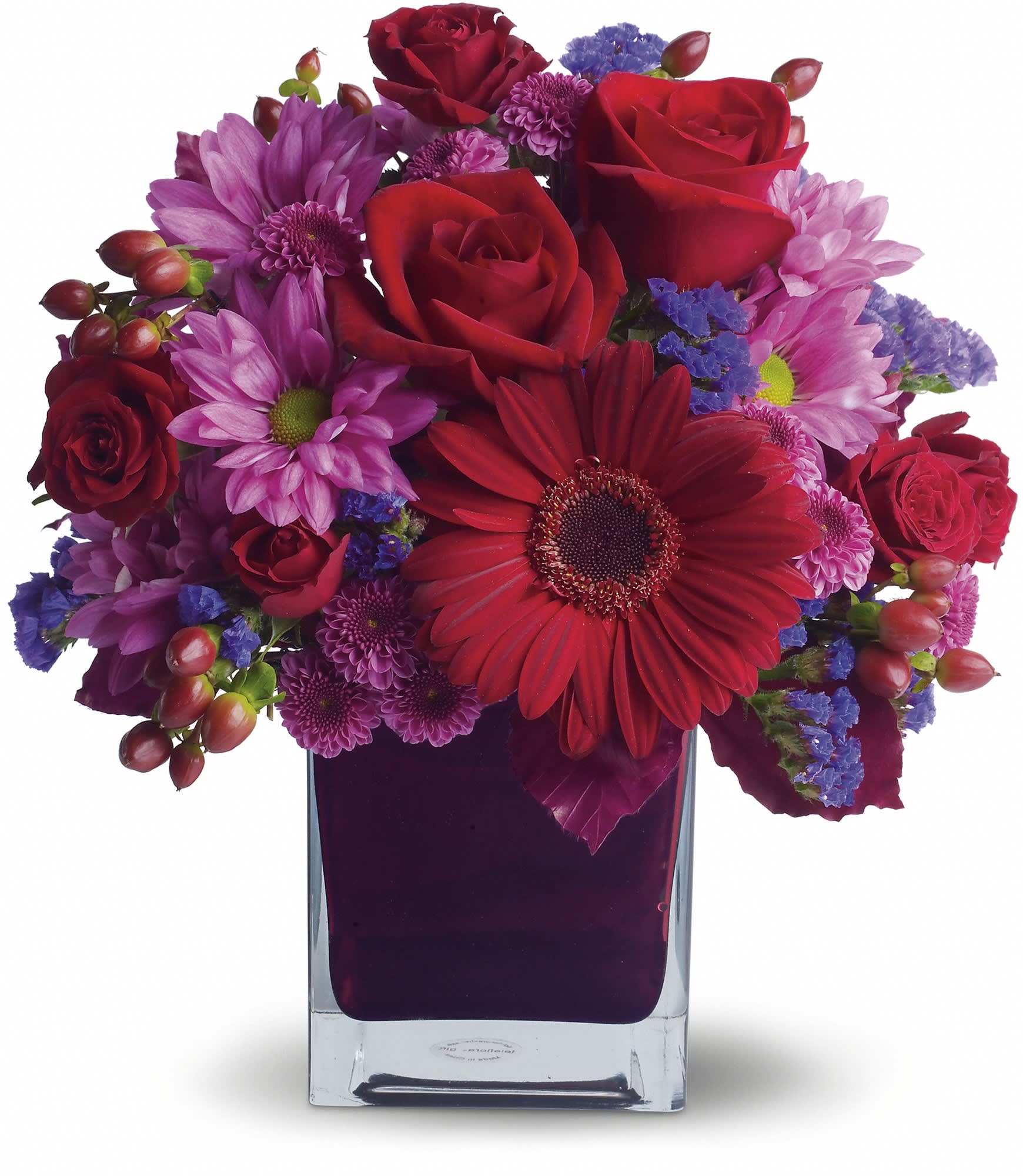 Red roses and purple daisies arranged in a clear square vase