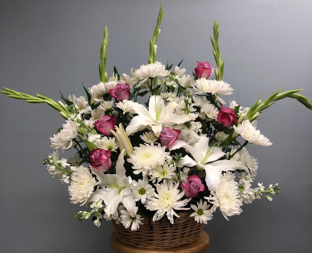Basket arrangement of white lilies, daisies, and pink roses