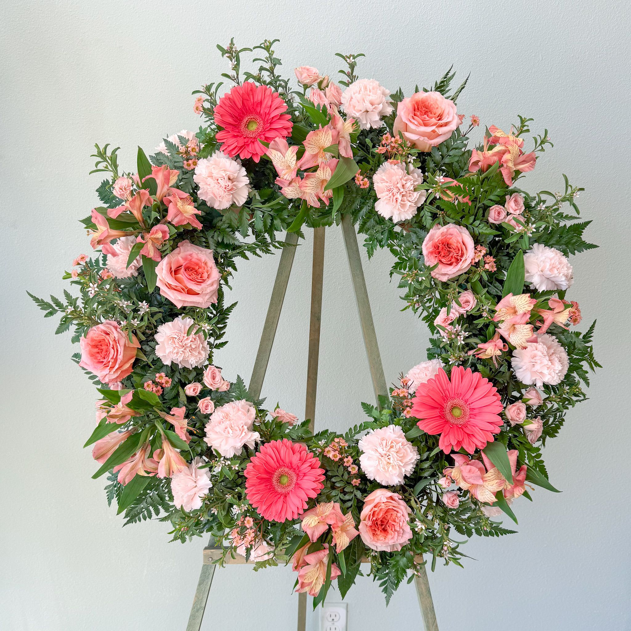 Warm Memories Wreath - The garden inspired wreath is a soft blend of blush, peach and coral. The Warm Memories Wreath is thoughtfully designed as a flowing composition of warmth and light that feels both comforting and refined. This wreath offers a beautiful tribute that honors cherished memories. 