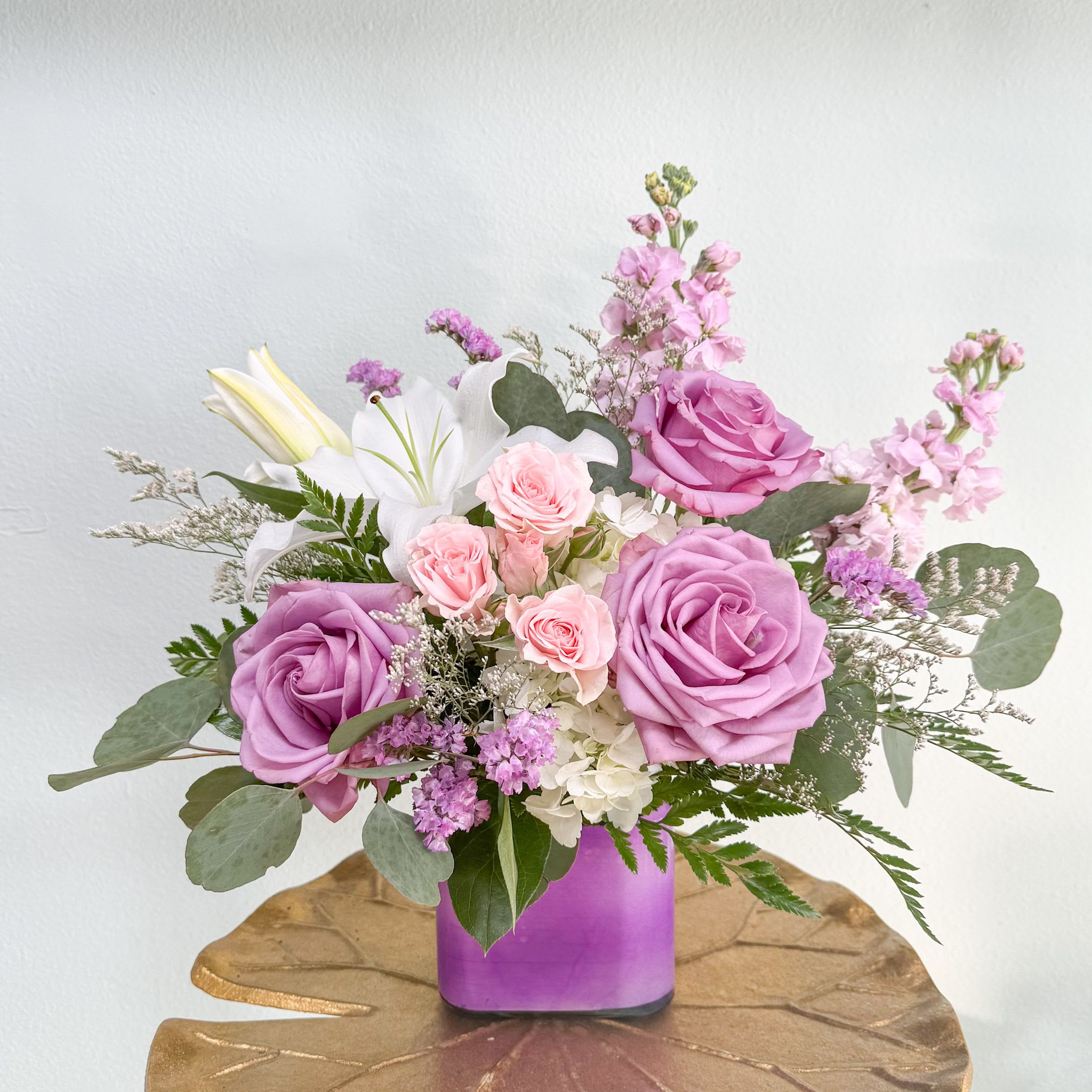 Serene Dream - No matter the occasion this soft and serene color palette is sure to please. Pink and lavender roses, fragrant stock and lilies, delicate filler are arranged in a lavender cube vase. The perfect way to show someone they are in your thoughts. 