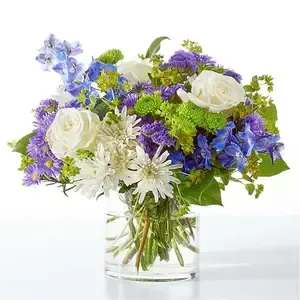 Bouquet of white roses, blue and purple flowers in a clear glass vase