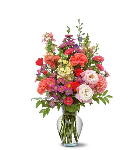 Mixed bouquet of pink, red, and purple flowers in a clear glass vase