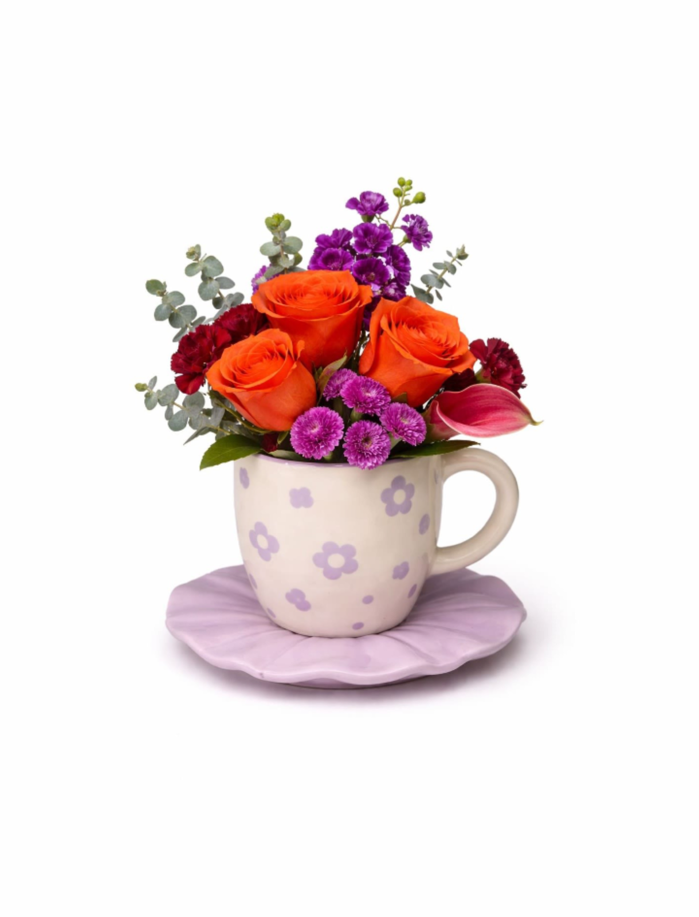 Compact orange and purple flower arrangement in a patterned mug on a lilac saucer