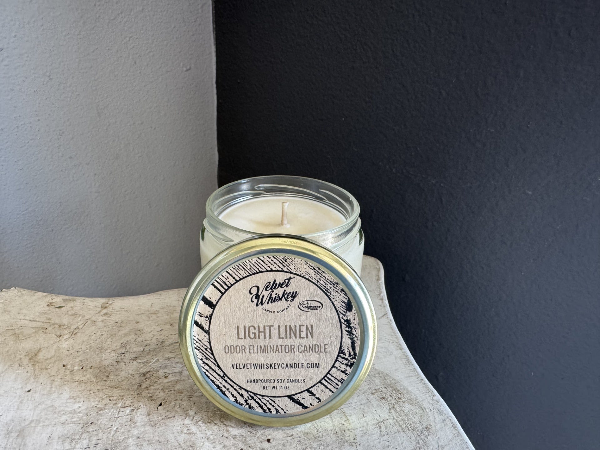 Glass jar candle with a labeled lid on a tabletop