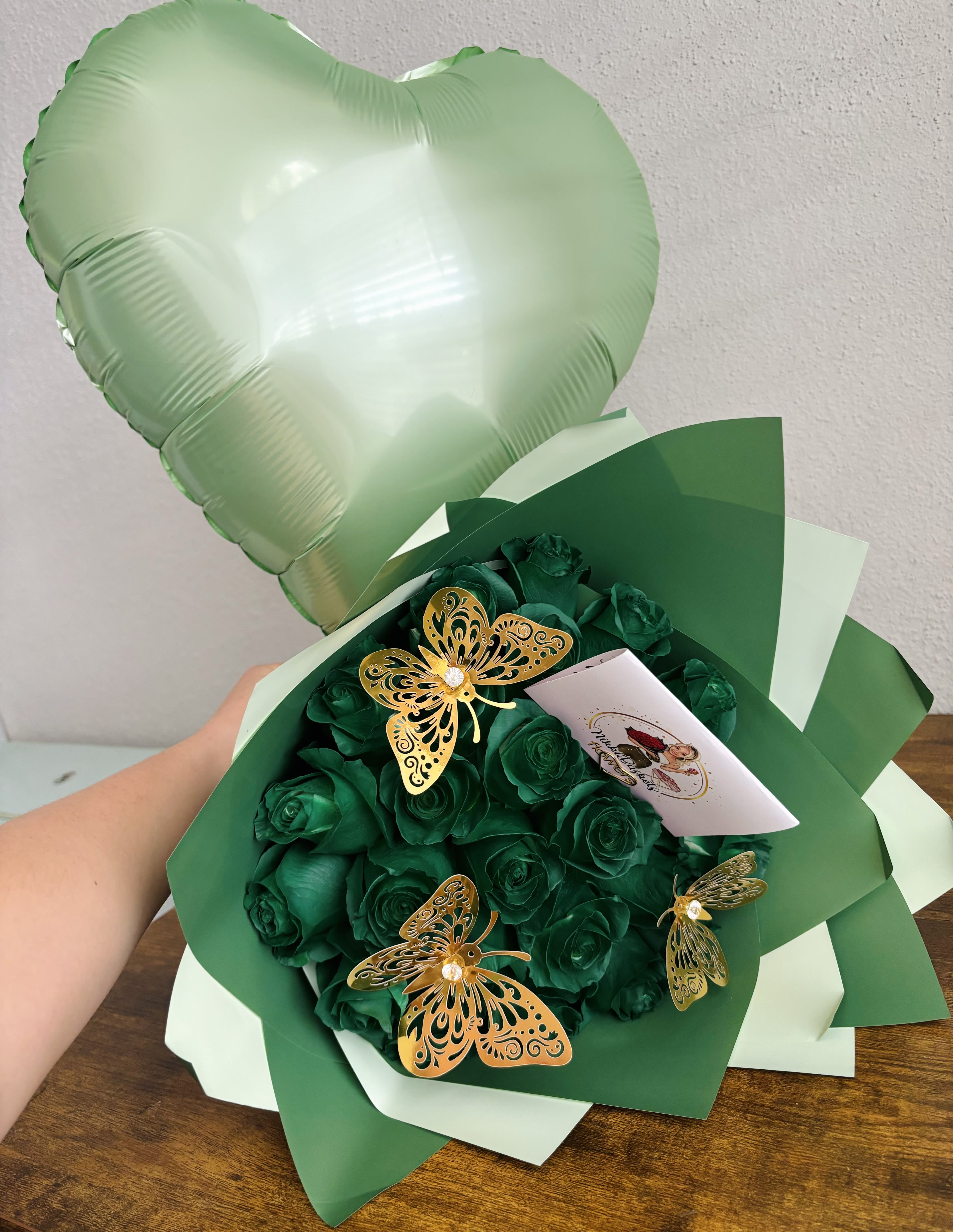 Emerald Green Rose Bouquet -  Green Roses Bouquet with Heart Balloon   This elegant arrangement features the freshness of green roses, adorned with delicate golden butterflies, and paired with a heart-shaped balloon. Wrapped in premium designer paper, it’s the perfect gift to express love, gratitude, or admiration in a unique and sophisticated way.