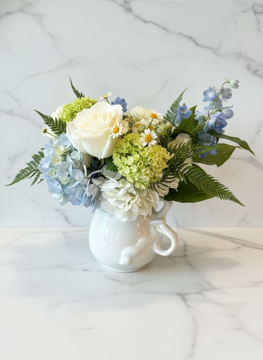 Summer Afternoon  - This arrangement reminds us an idyllic summer afternoon - a pitcher of lemonade, lush sprigs of hydrangea and sweet herbs. It's perfection.  Designed in a charming reproduction ironstone pitcher with bow motif handle - sure to be enjoyed after the flowers have passed.  approx. 10x10 