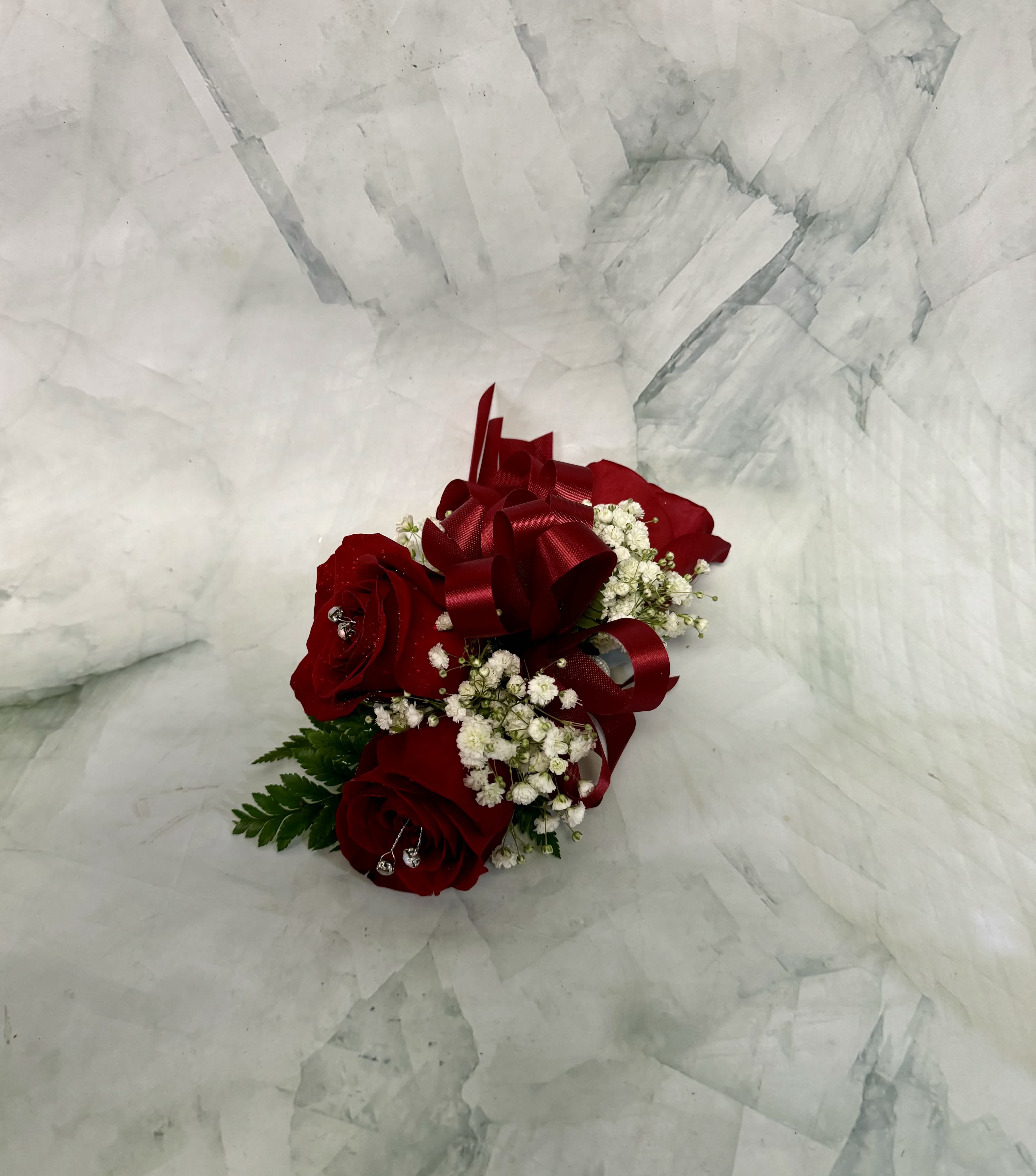 Red rose corsage with white baby's breath and a burgundy ribbon