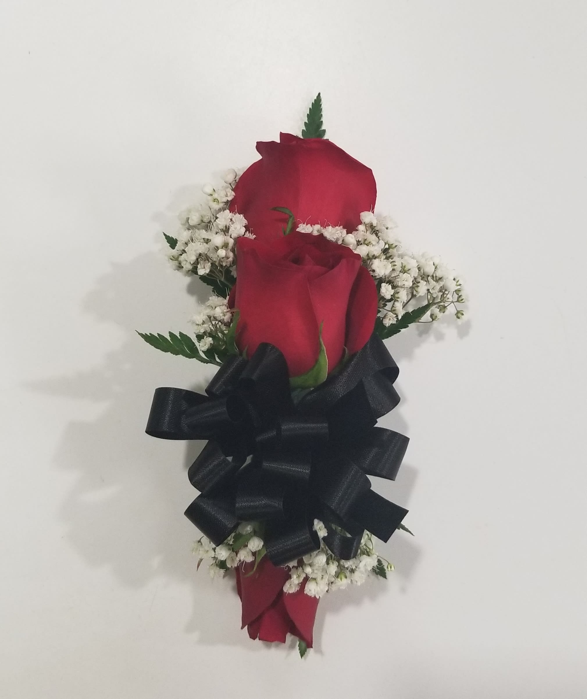 Two red roses with white baby's breath and a black ribbon
