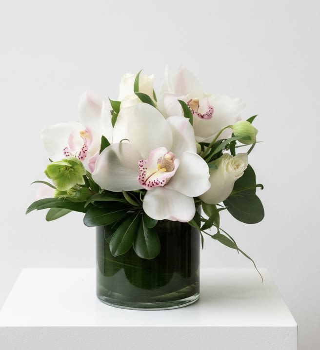 Orchids and roses - For a gift that's both luxurious and lovely, consider a bouquet of exotic fresh white orchids accented with tiny pink blossoms, arranged in a leaf-lined glass cube vase. It's a bit of the tropics, delivered with a smile!   