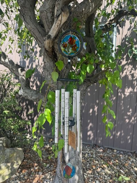 Wind chime hanging from a tree branch with stained-glass accents
