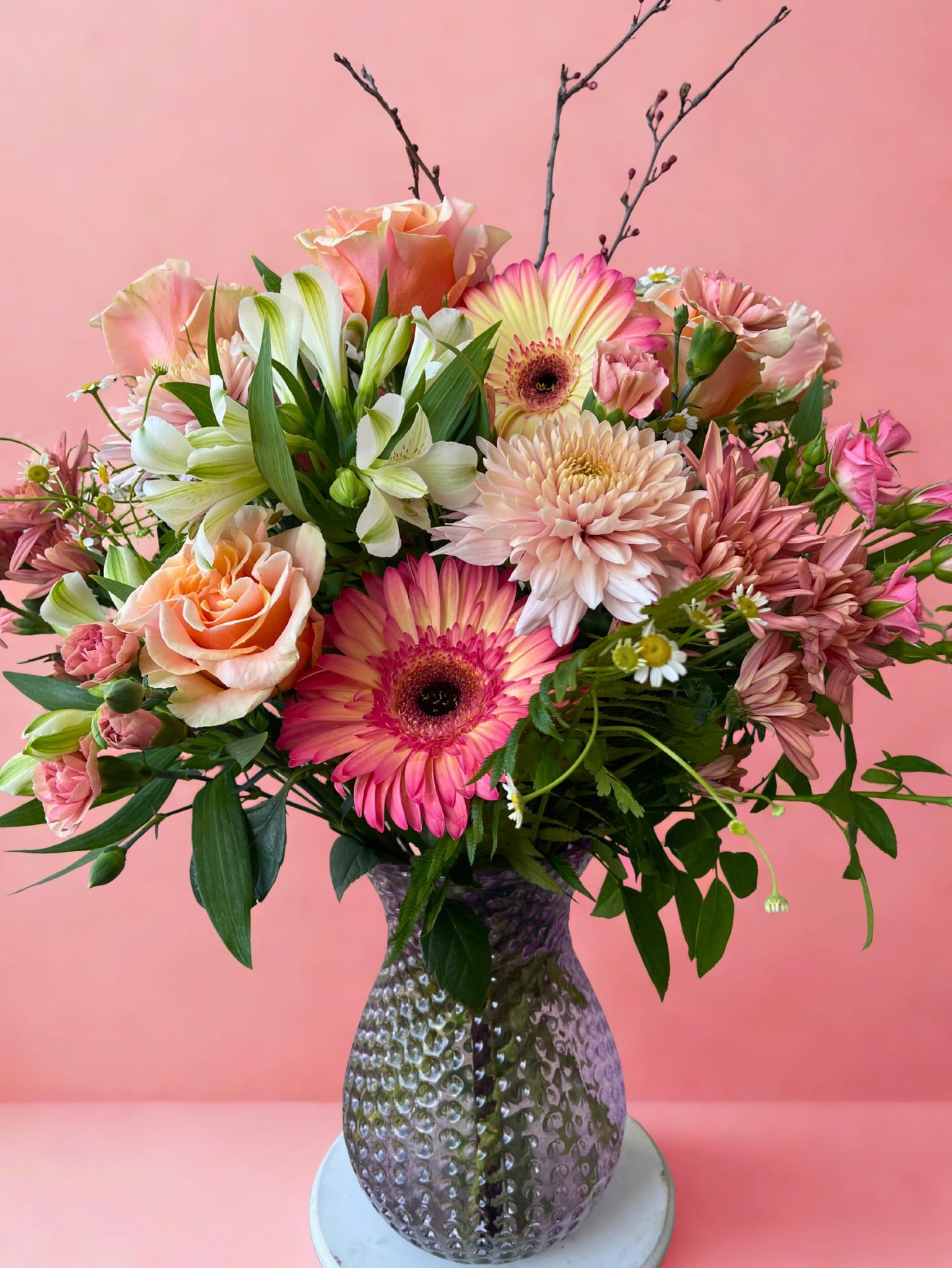Mixed pink and peach bouquet in a textured glass vase