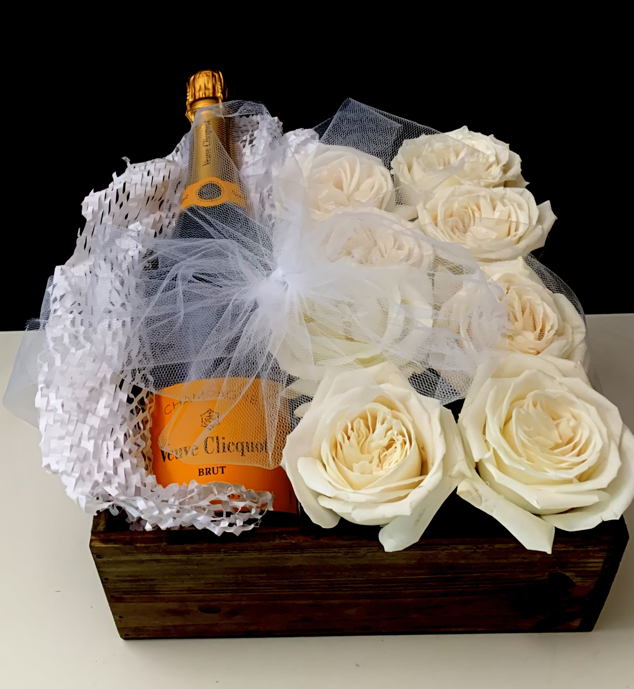 Champagne bottle in a wooden box with white roses and tulle