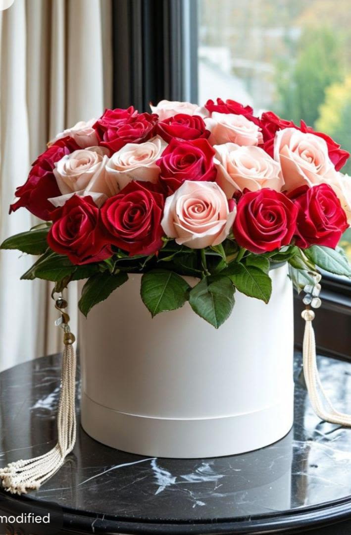 Red and blush roses arranged in a white round box