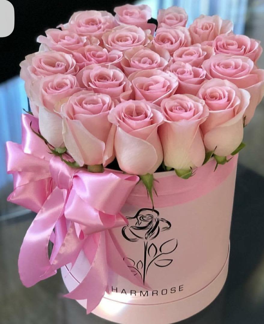 Pink roses arranged in a round hat box with a satin ribbon