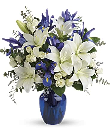 White lilies and blue iris in a blue glass vase
