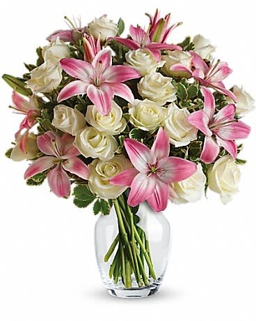 Pink lilies and white roses arranged in a clear glass vase