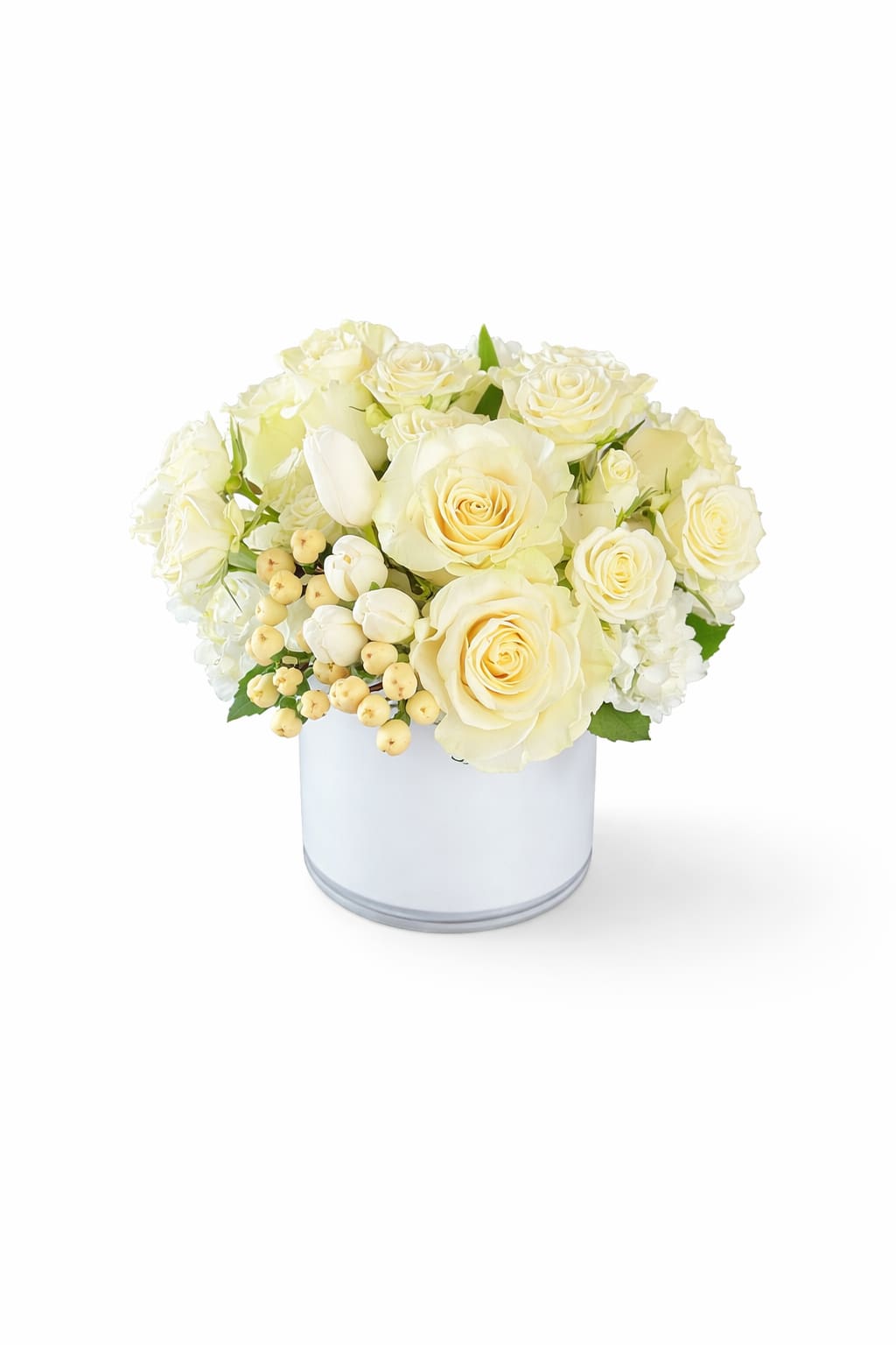 Sauvignon Blanc - Cream-and-ivory roses clustered with pale white tulip buds create an elegant, serene centerpiece perfect for a wedding bouquet, sympathy arrangement, or a thoughtful everyday gift. The soft, light palette-ivory, white, touches of pale yellow and green-gives the recipient a calm, comforting impression that says you care without overwhelming.  The arrangement is gathered tightly and presented in a smooth white cylindrical vase for a clean, polished silhouette. Textural interest comes from the creamy rose petals, the soft tulip buds, and subtle pale berry accents that add depth while keeping the look refined. Sized to sit beautifully on a dining table, console, or bedside, it arrives ready-to-display with water in the vase for immediate enjoyment.