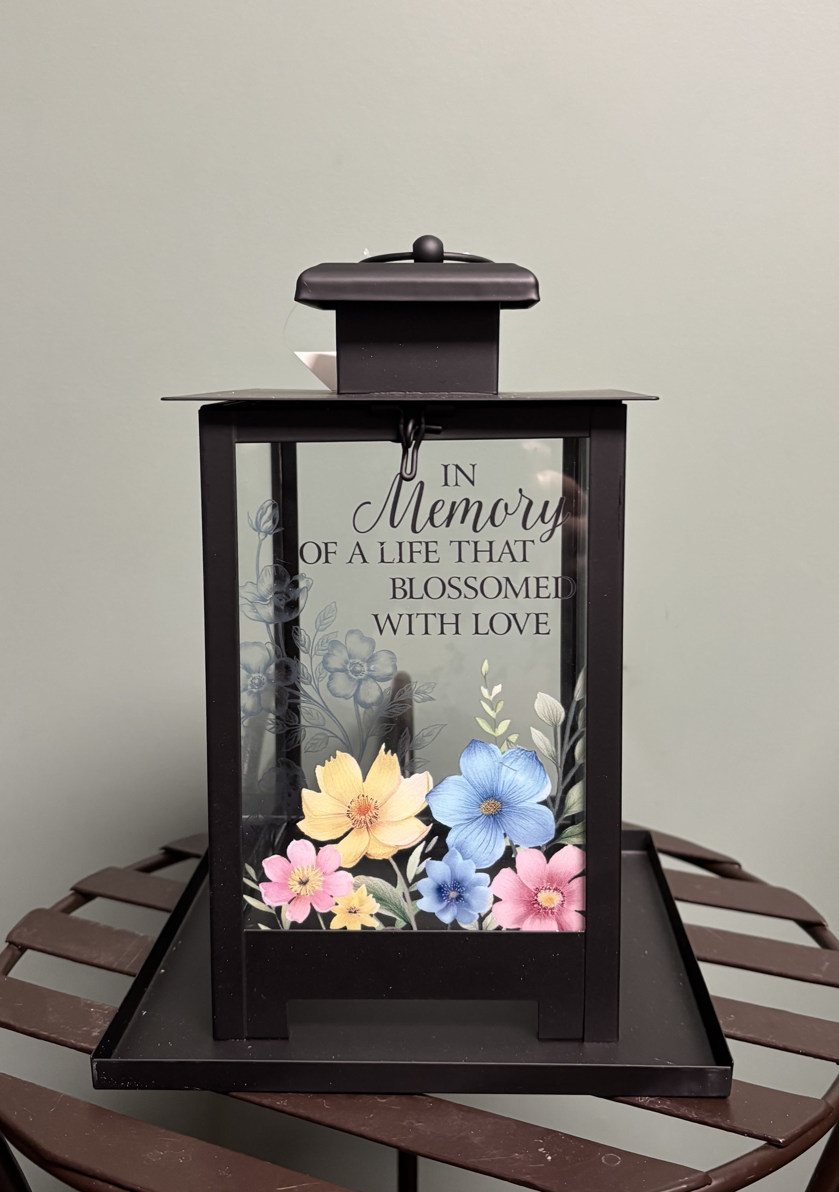 "In Memory" Sympathy Bird Feeder - A new and unique item in our collection of lasting sympathy gifts.  This black metal birdfeeder measures 7 x 7 inches square on the bottom and is 10 inches high.  On the front panel the saying "In Memory of a life that blossomed with love" as well as pastel florals painted across the front panel..  A truly inspiring gift for those who love nature.