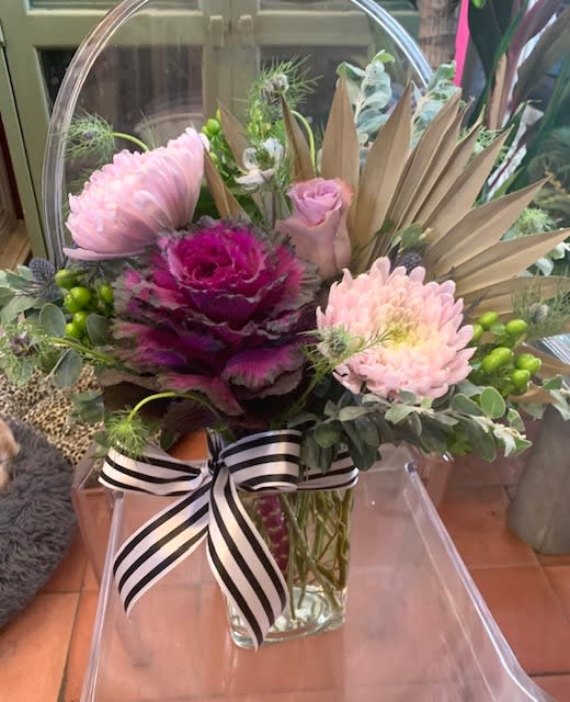 Pink and magenta floral arrangement in a clear glass vase with a striped ribbon