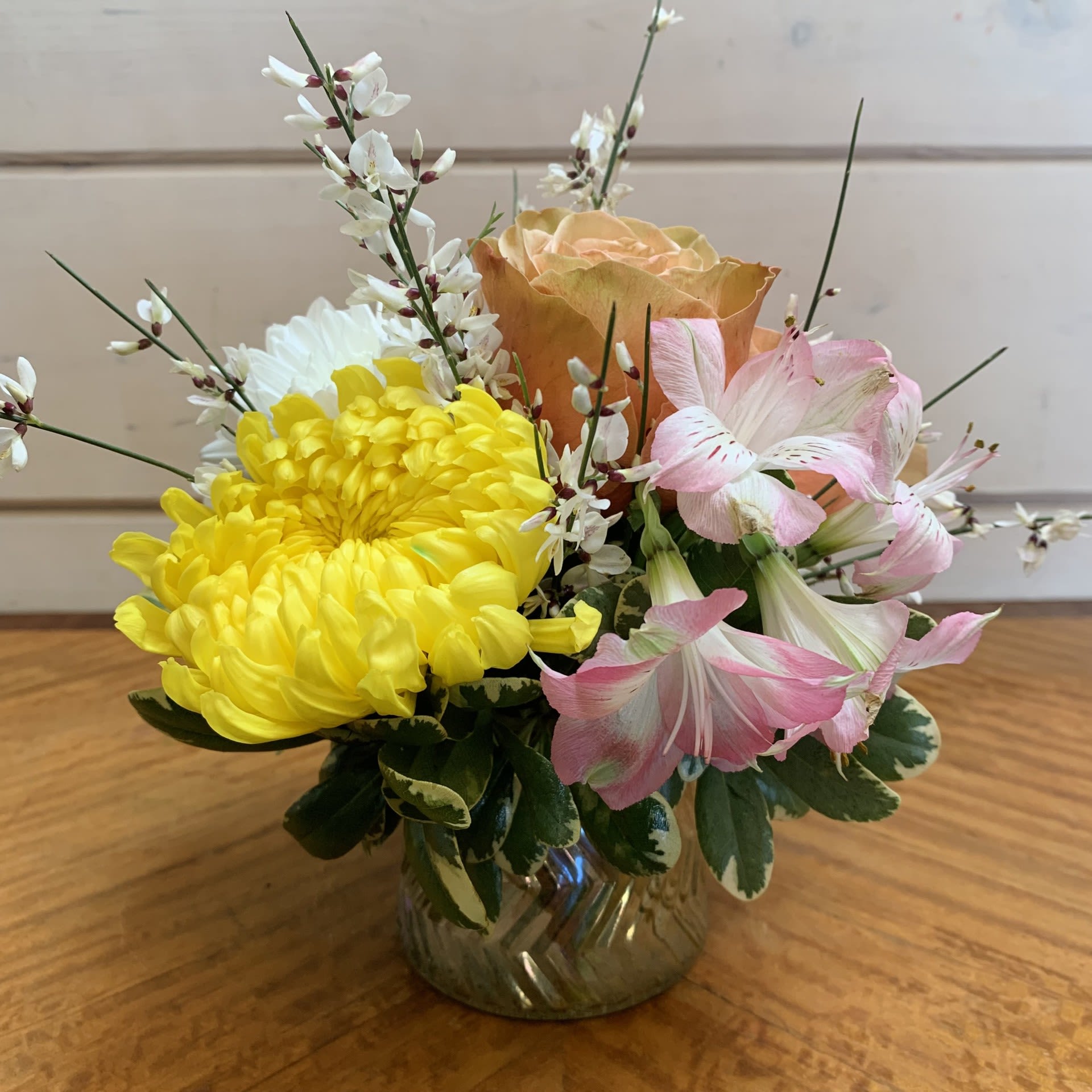 Yellow and pink flowers arranged in a small glass vase