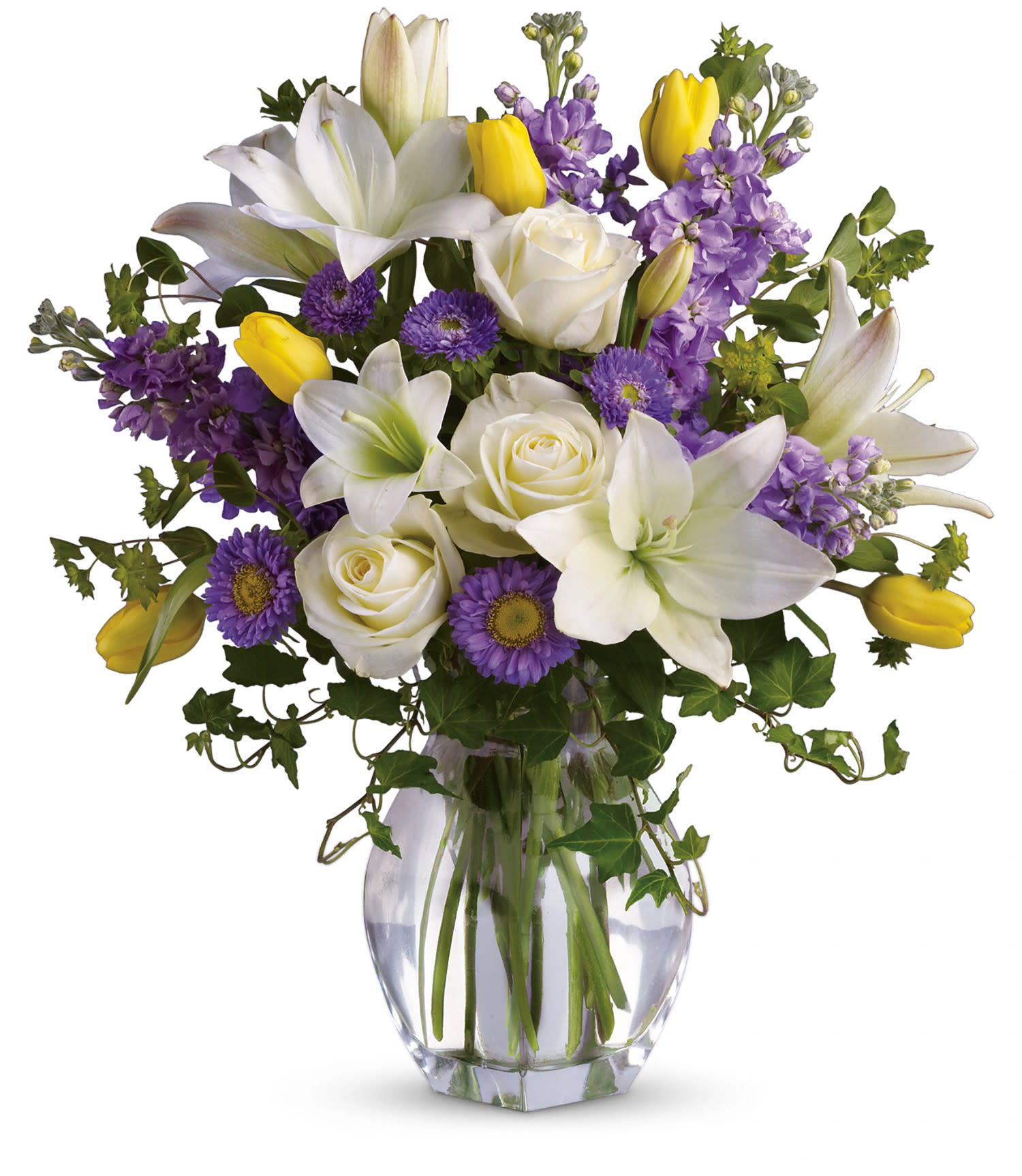 White lilies, roses, purple flowers, and yellow tulips in a clear glass vase