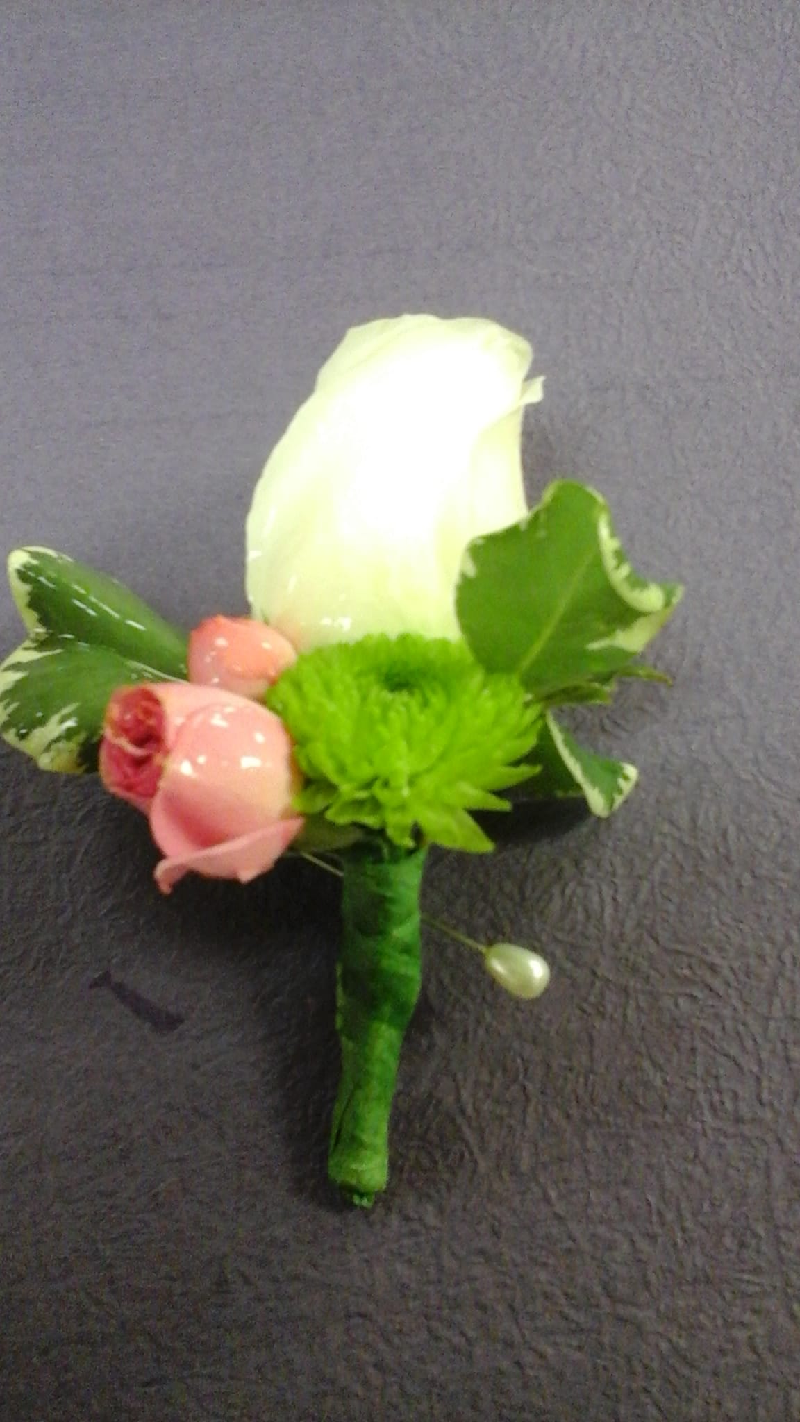 Boutonniere with a white rose, pink rosebud, and green accent flower