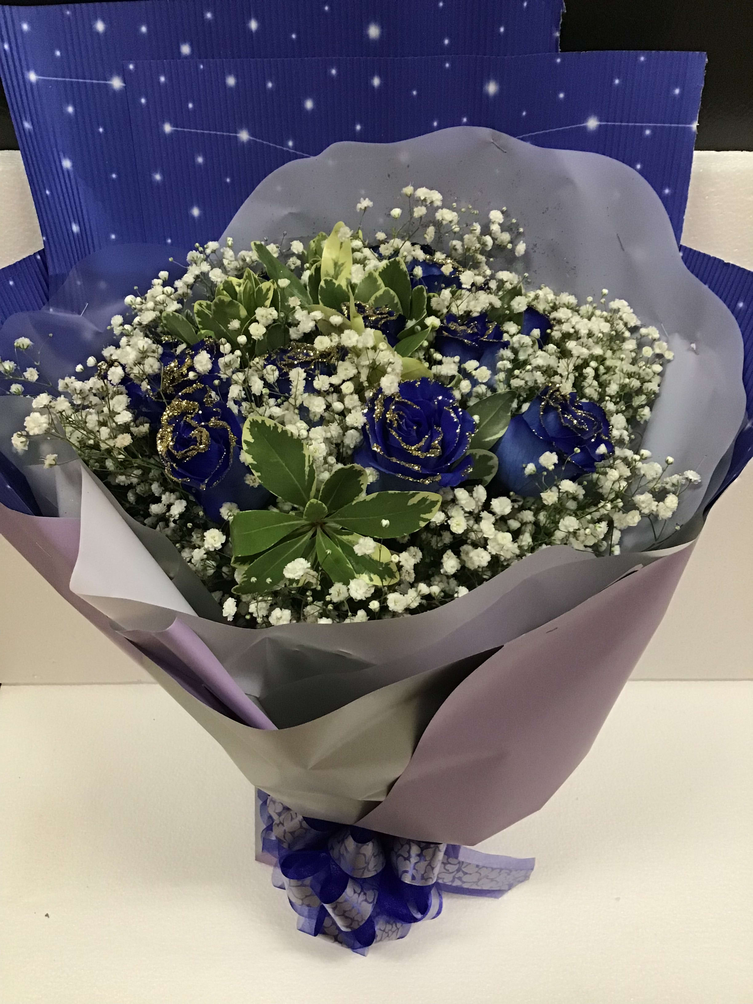 Blue roses with baby's breath in purple wrapping