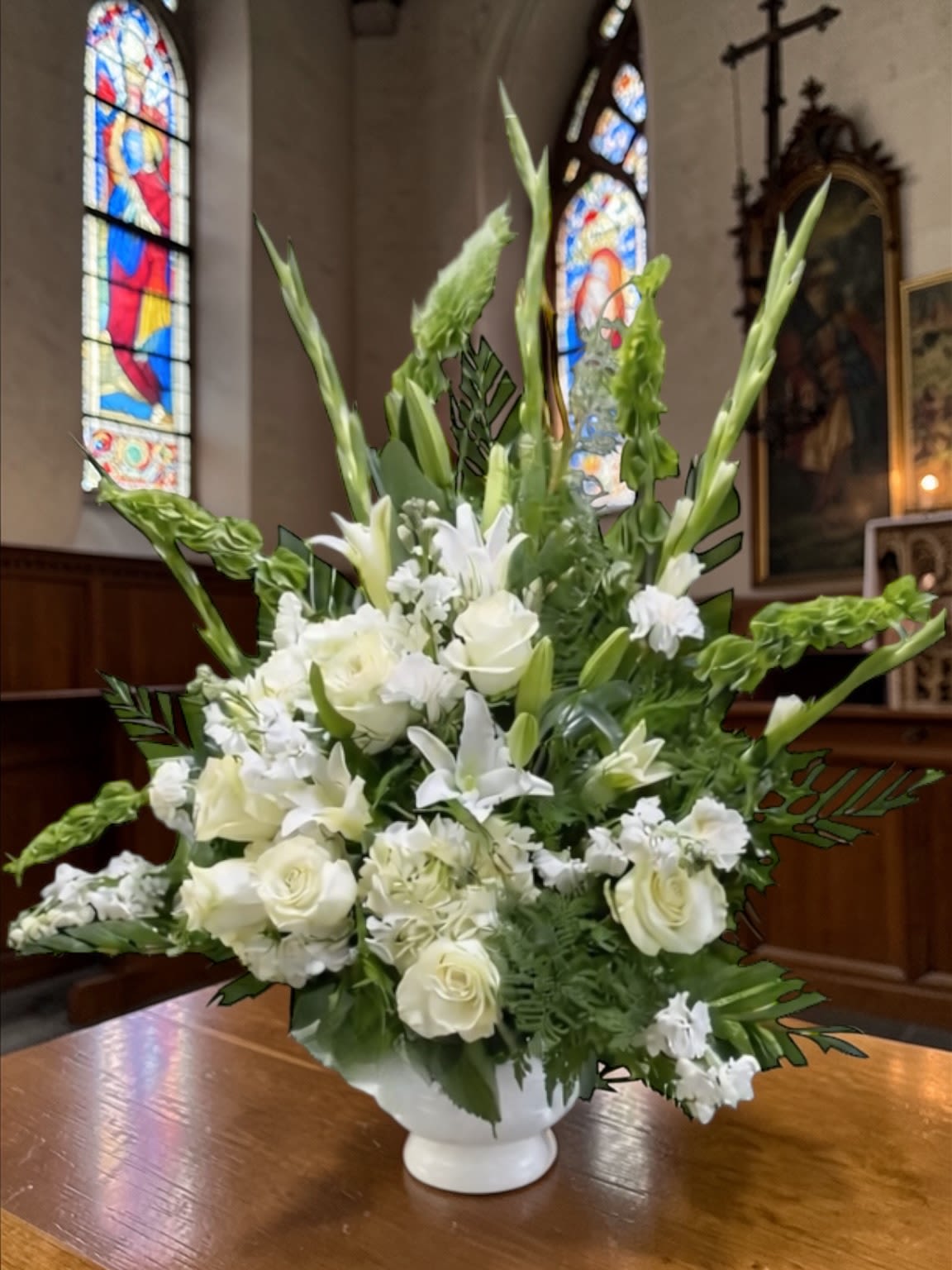 Loving Thoughts Spray - Loving Thoughts is a graceful sympathy spray designed to express heartfelt condolences and loving remembrance. A classic blend of white blooms—including gladiolus, lilies, roses, chrysanthemums, and bells of Ireland—is arranged with rich greenery to create a design that feels peaceful, dignified, and timeless.  The vertical form gives it natural height and presence, allowing it to stand beautifully at the service while maintaining a calm, composed feel. The all-white palette reflects purity, respect, and enduring love without distraction.  A meaningful choice for funeral services, memorial gatherings, or sending comfort to a grieving family.  Each arrangement is created with the freshest stems available. Subtle variations may occur while preserving the overall style and color palette.  Available for standing spray delivery through Aspen Tower Florist, serving Greensburg and Shelbyville along with Rushville, Batesville, Westport, Oldenburg, St. Paul, Waldron, Milroy, and Hope.