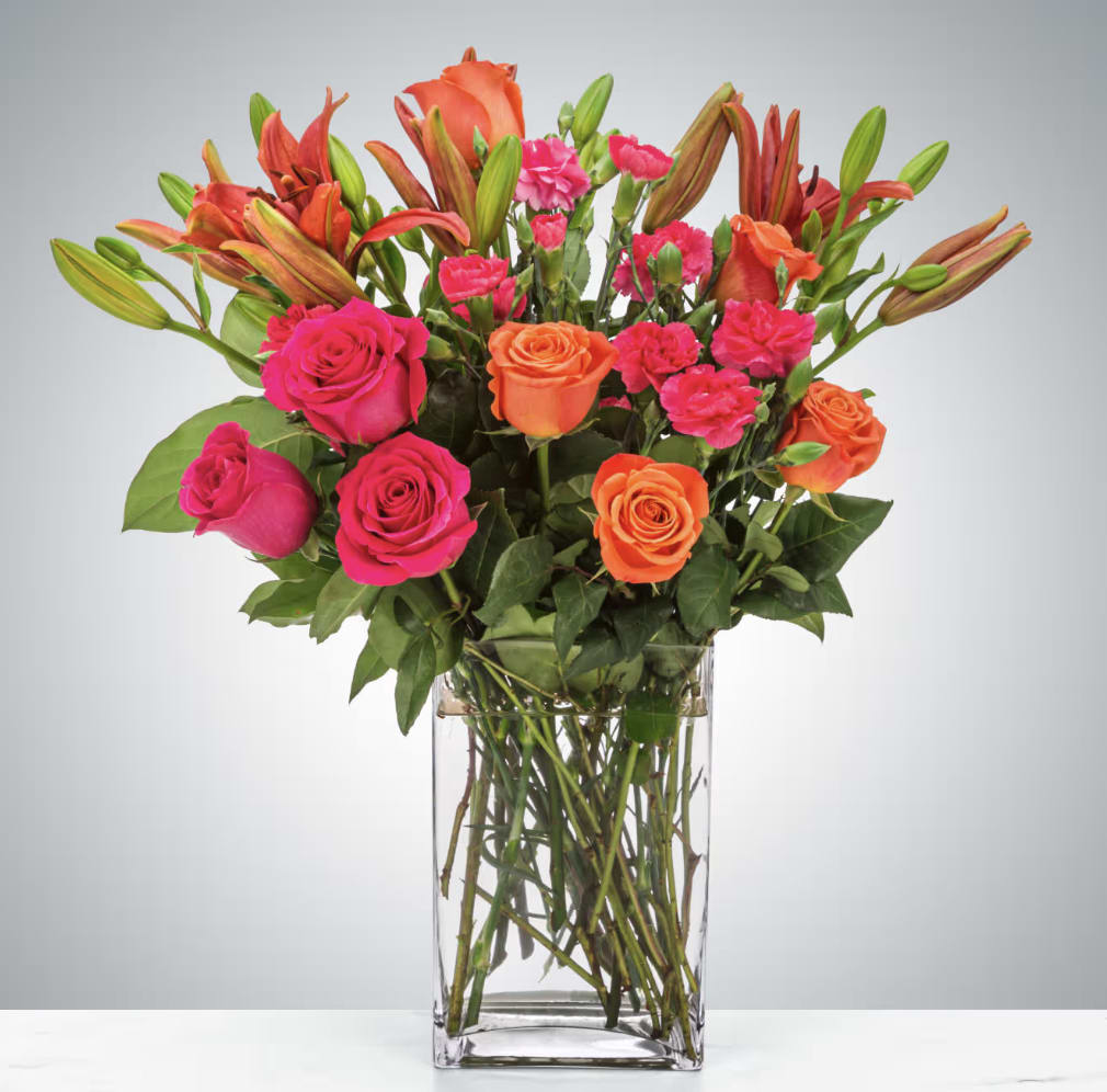 Bouquet of pink and orange roses with lilies in a clear glass vase