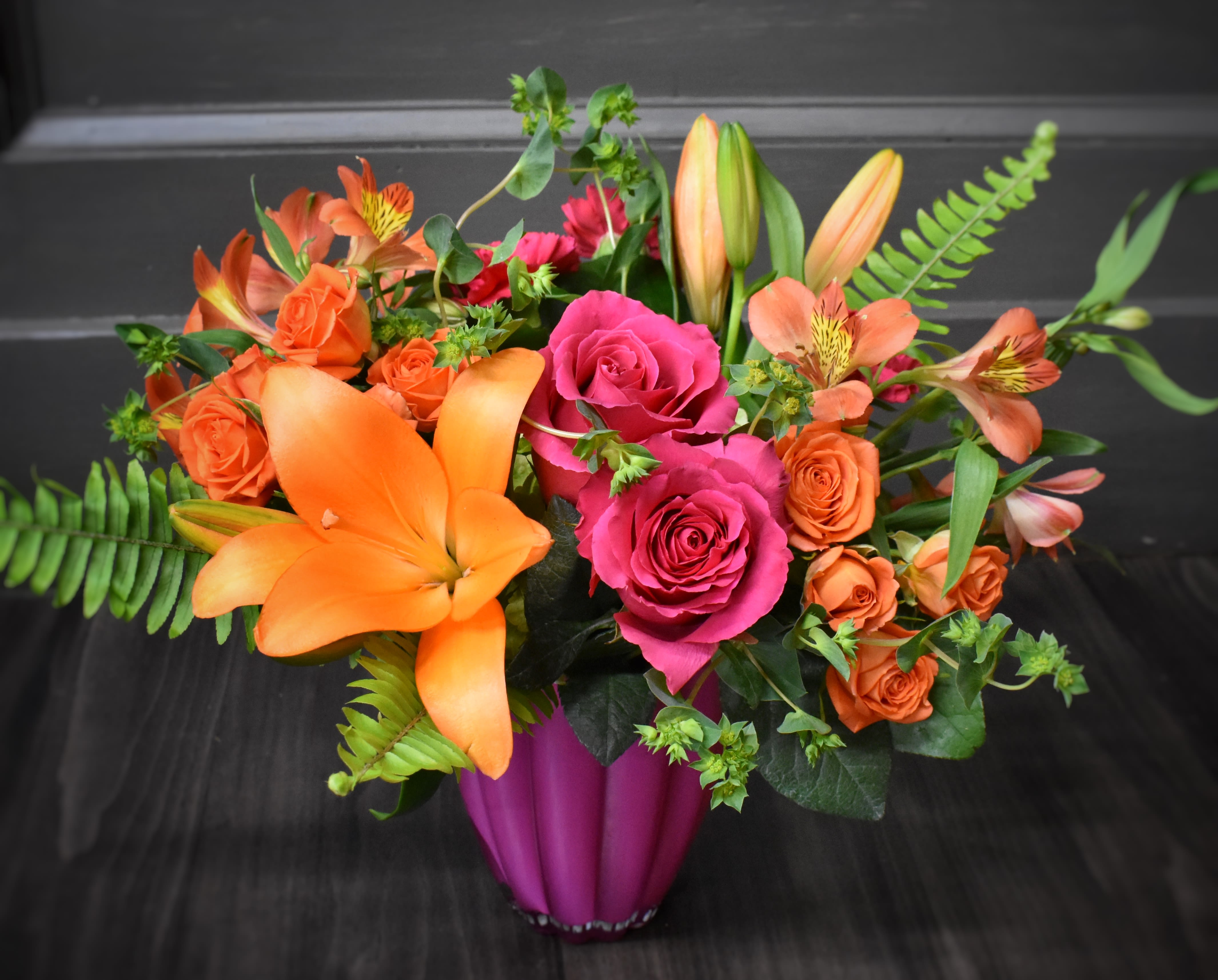 Bouquet of orange lilies and pink roses in a magenta vase