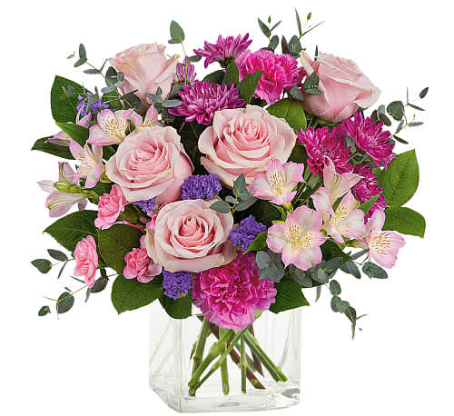 Pink roses and mixed blooms arranged in a clear glass vase