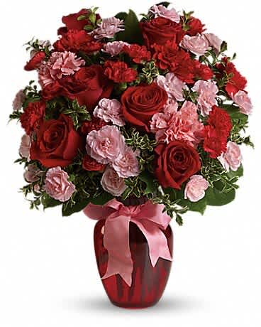 Red roses and pink carnations in a red vase with a pink ribbon