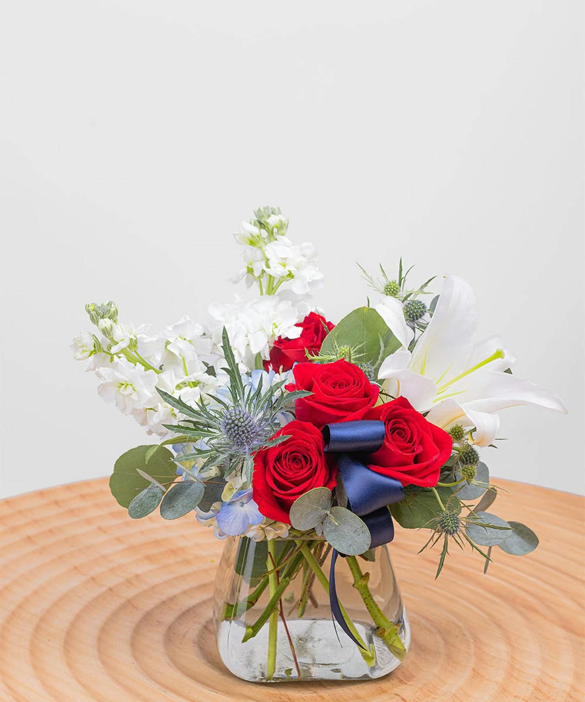 Starry Stock Arrangement - This patriotic floral arrangement is designed with a classic red, white, and blue color palette, and is accentuated by lush green leaves to round out a garden-inspired feel.