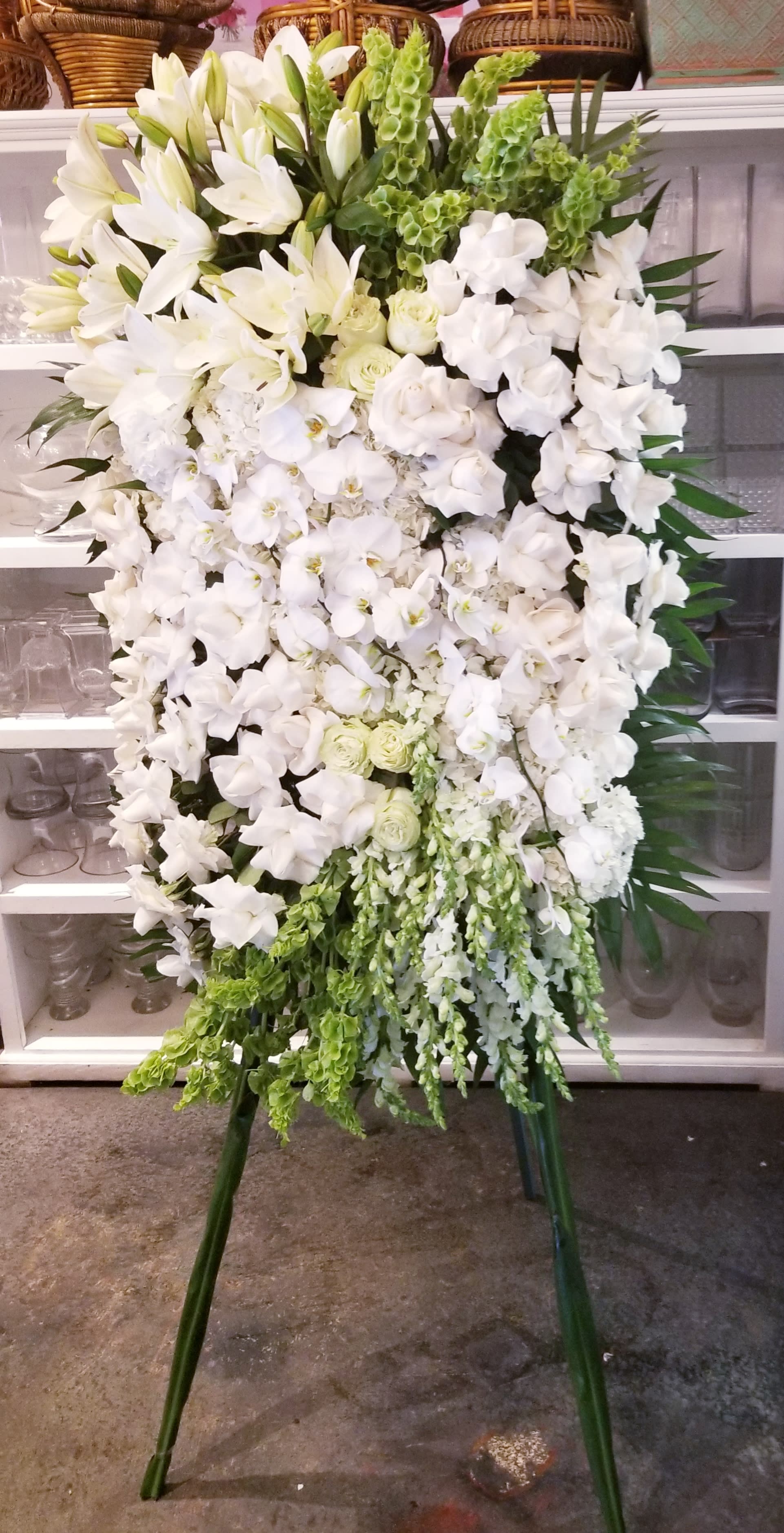 Tall white floral standing spray on an easel with green accents